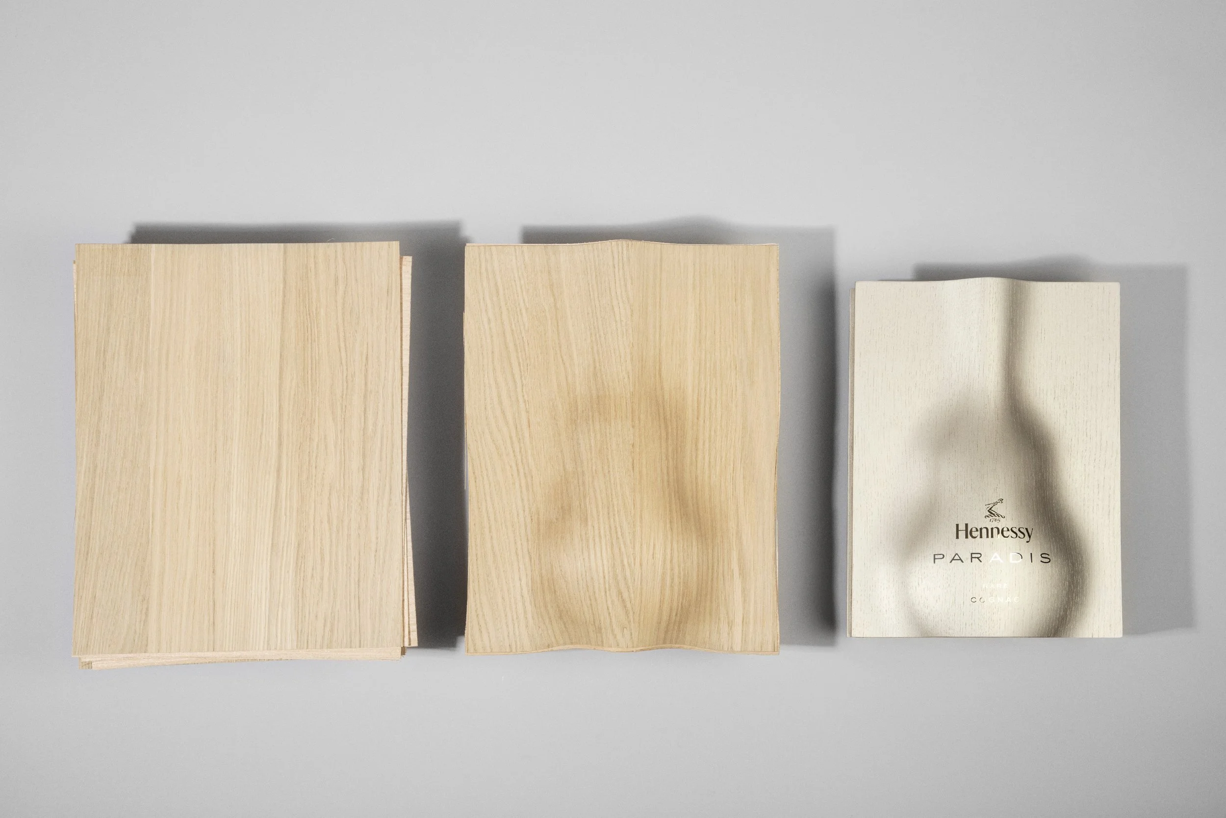 Three stacks of papers or cards laid out on a gray surface, with the rightmost stack featuring a white background with a leaf illustration and the word 'Hennessy' and 'Paradis' printed on it.