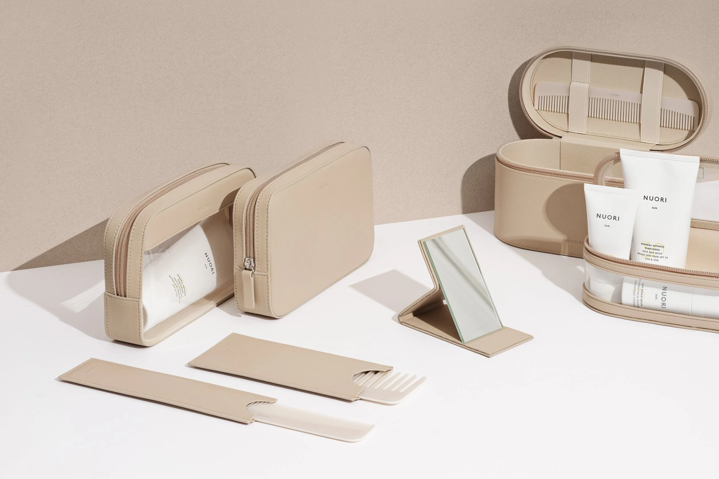 Beauty products and accessories including creams, a mirror, and pouches in beige color on a white surface.