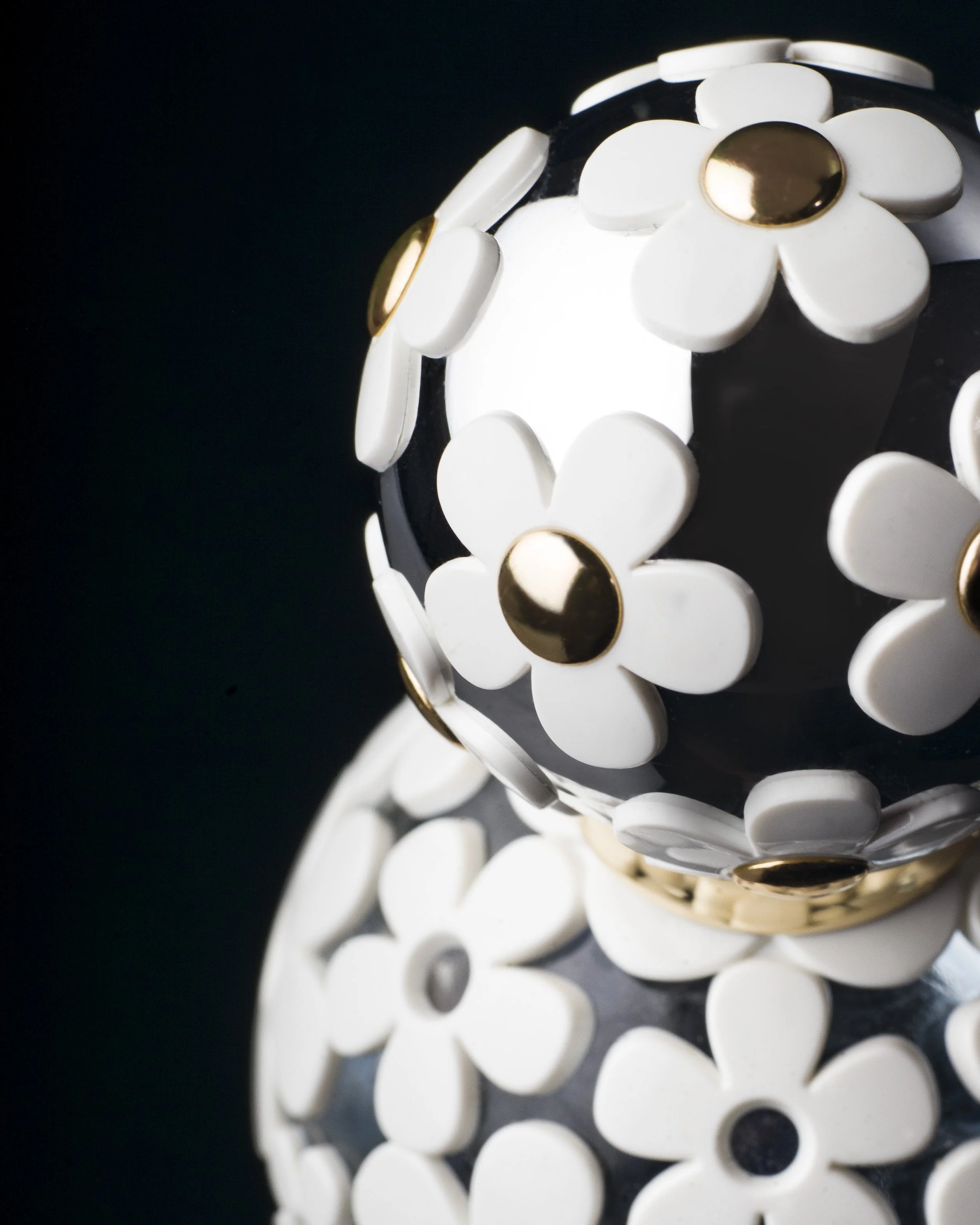 Decorative black and white spherical objects adorned with white flower motifs and gold accents.