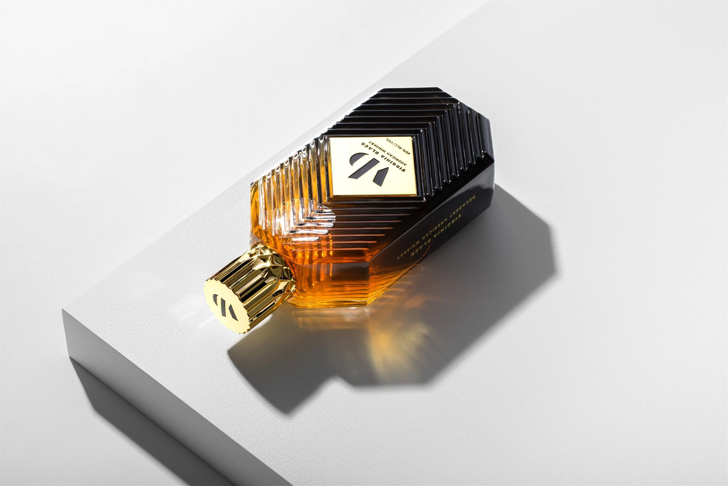 A perfume bottle with a ribbed design, black and gold accents, and the number 1 on the label, resting on a white surface with a shadow cast to the side.