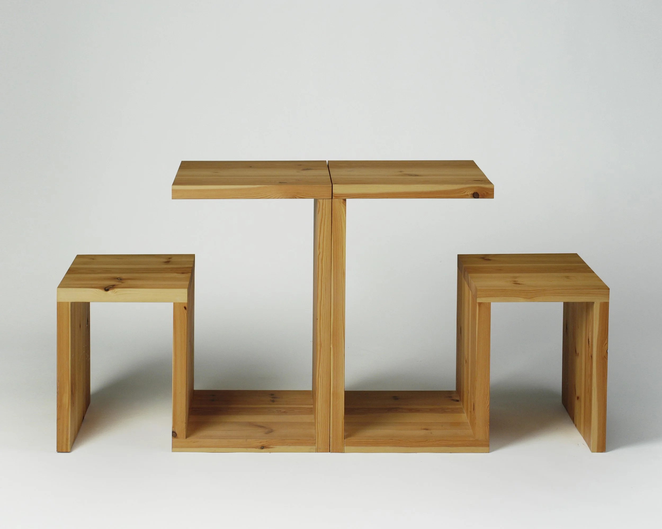 Set of three minimalist wooden furniture pieces, two small stools and a high table, arranged against a plain white background.