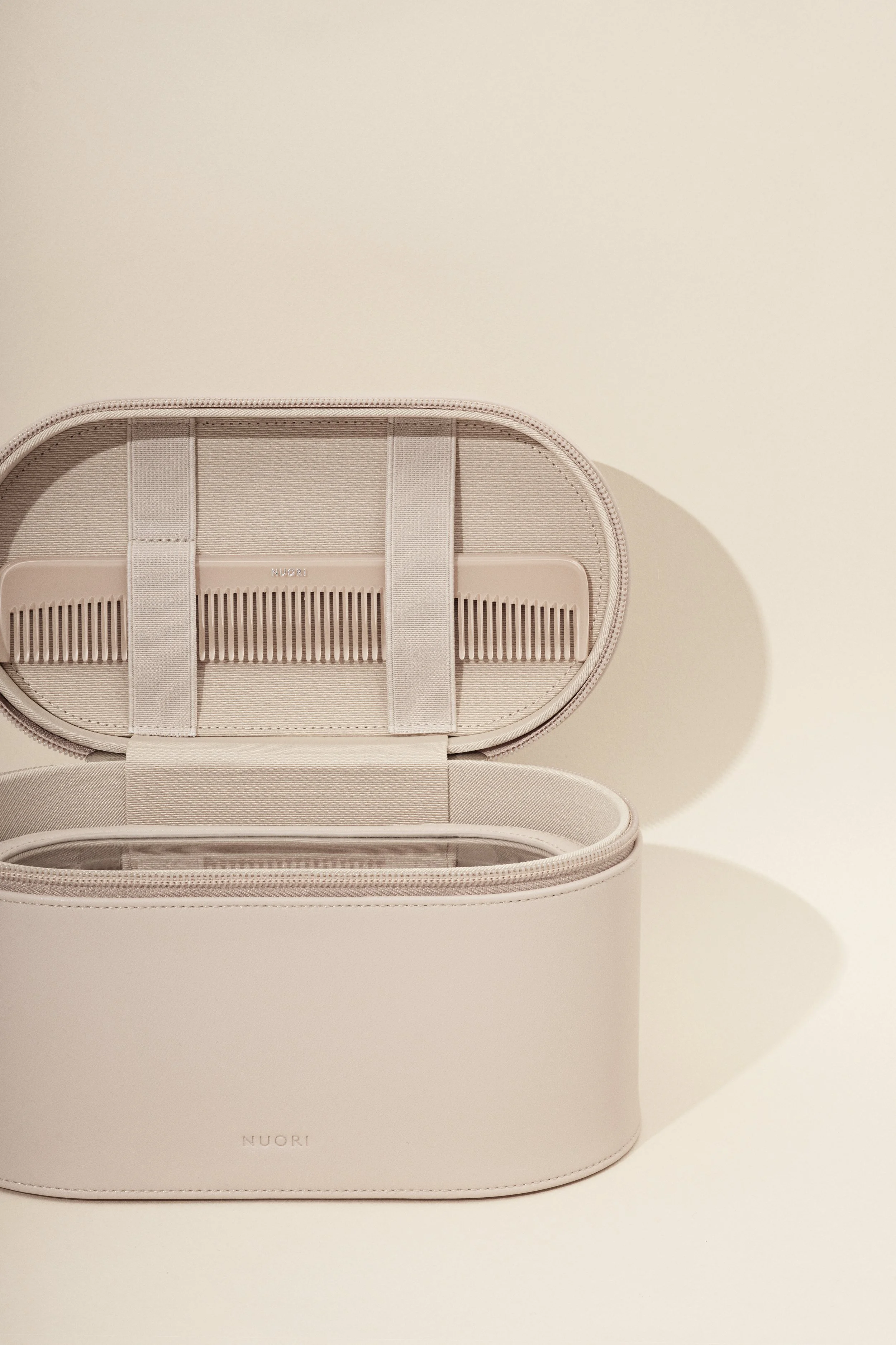 Open beige NUORI storage case with interior compartments against a light beige background.