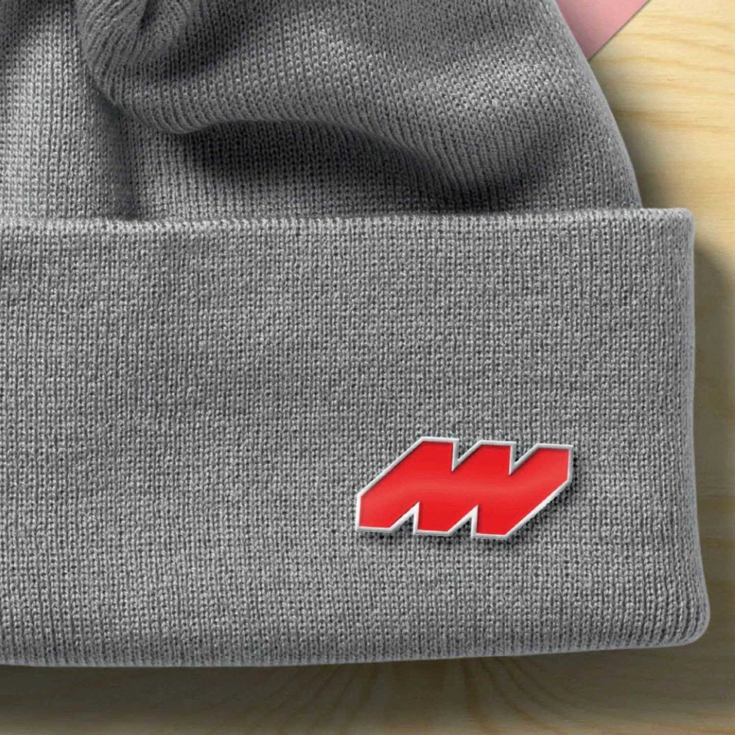 Gray knit fabric hat with a red and white logo patch.