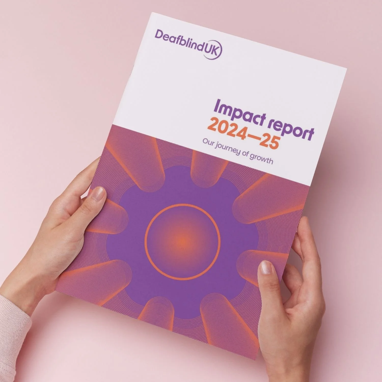 Person holding a report titled 'Impact report 2024-25' from Deafblind UK with a purple and orange abstract design on the cover, against a pink background.