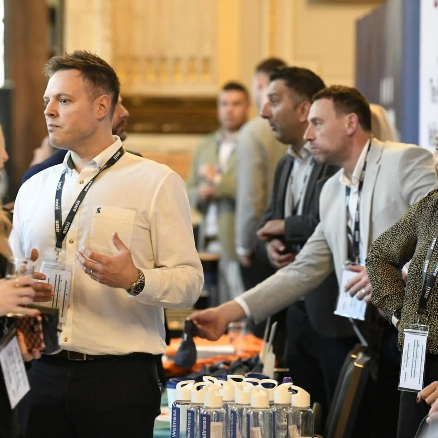 Attendees at a conference or event standing around a table with hand sanitizer bottles.