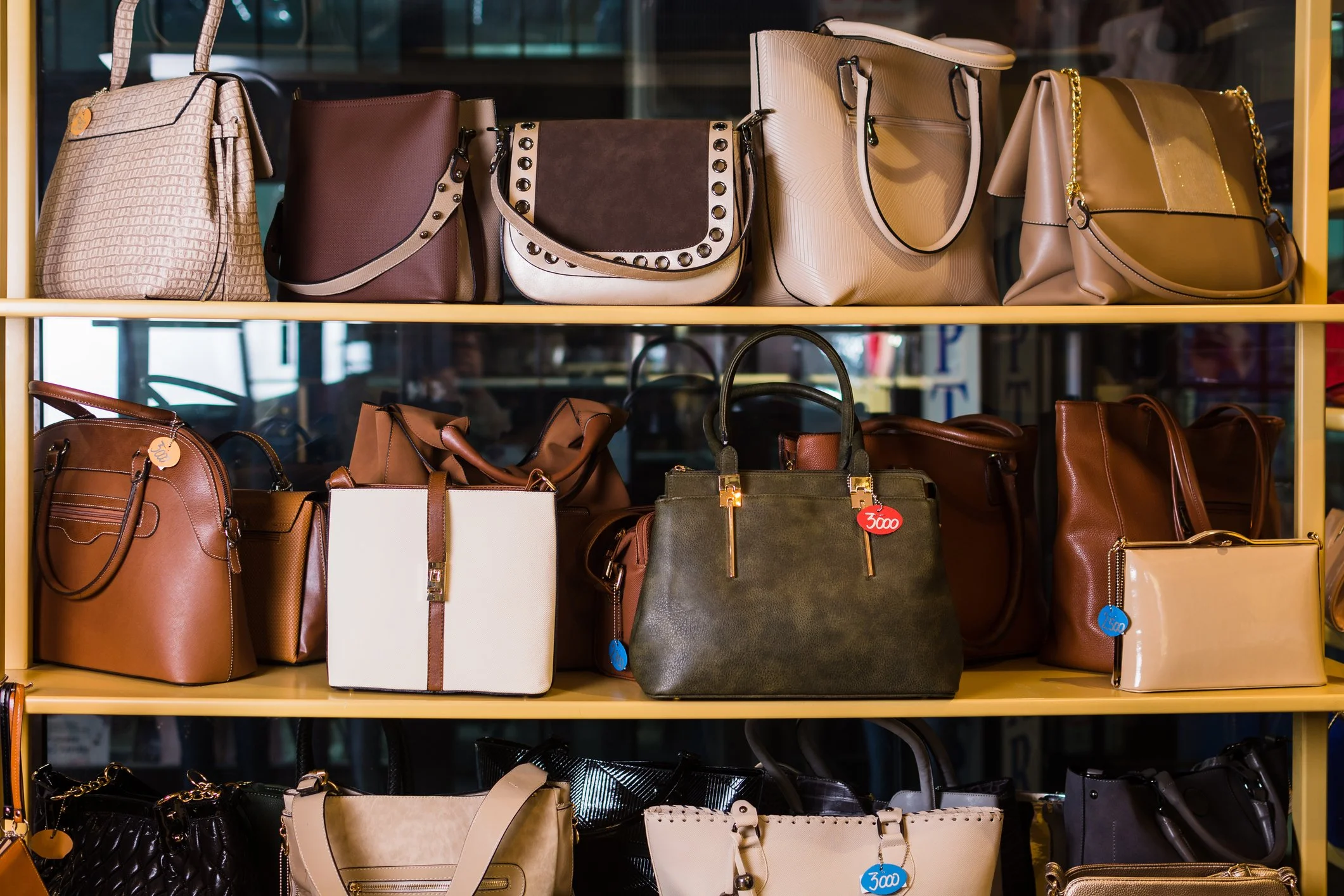 Display of various handbags on yellow shelves in a store.