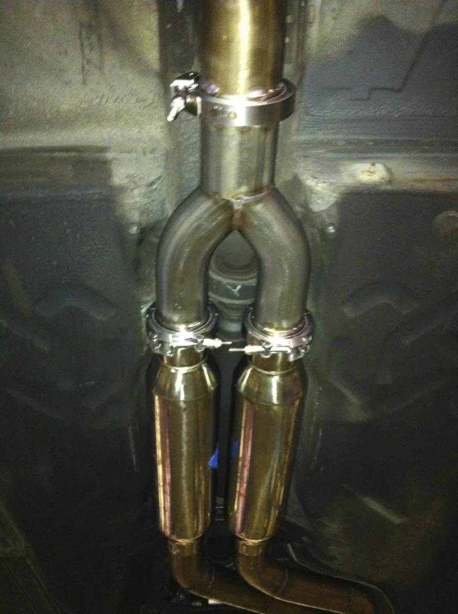 Under the car, there is a custom exhaust pipe system with two parallel mufflers and a Y-shaped pipe connecting to the mufflers.