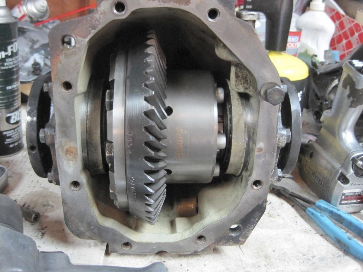 Disassembled engine with visible internal gears and components on a workbench, surrounded by tools and supplies.