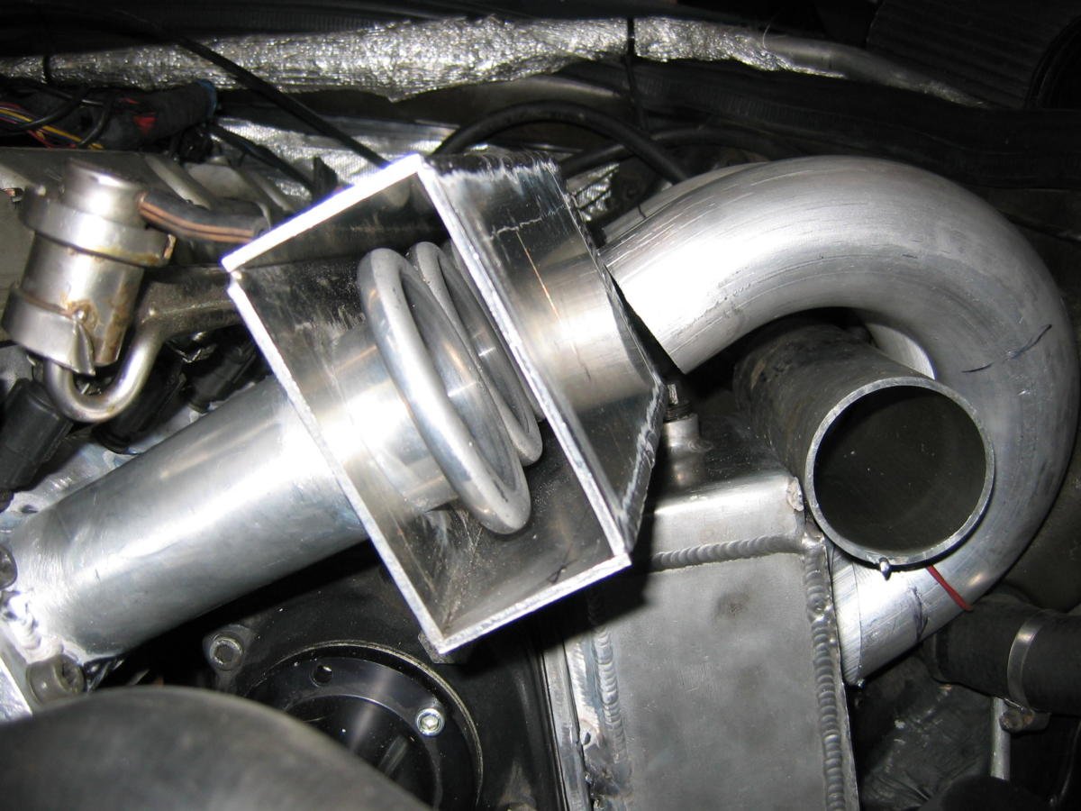 Close-up view of a turbocharger exhaust system with metallic pipes and components in an engine.
