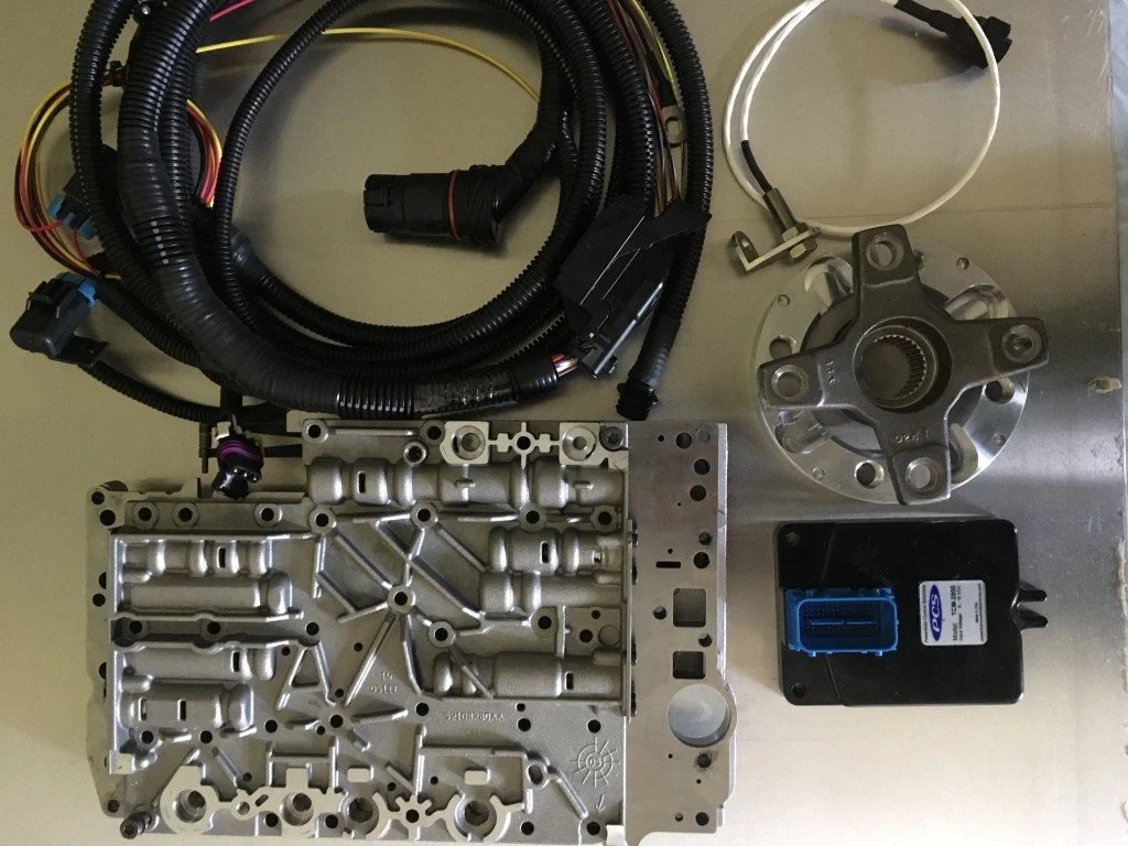 Automotive wiring harness, valve body, torque converter, and electronic component on a metal surface.