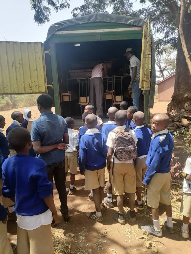  Students are gathered to help receive some of the new desks that arrive at the school. 