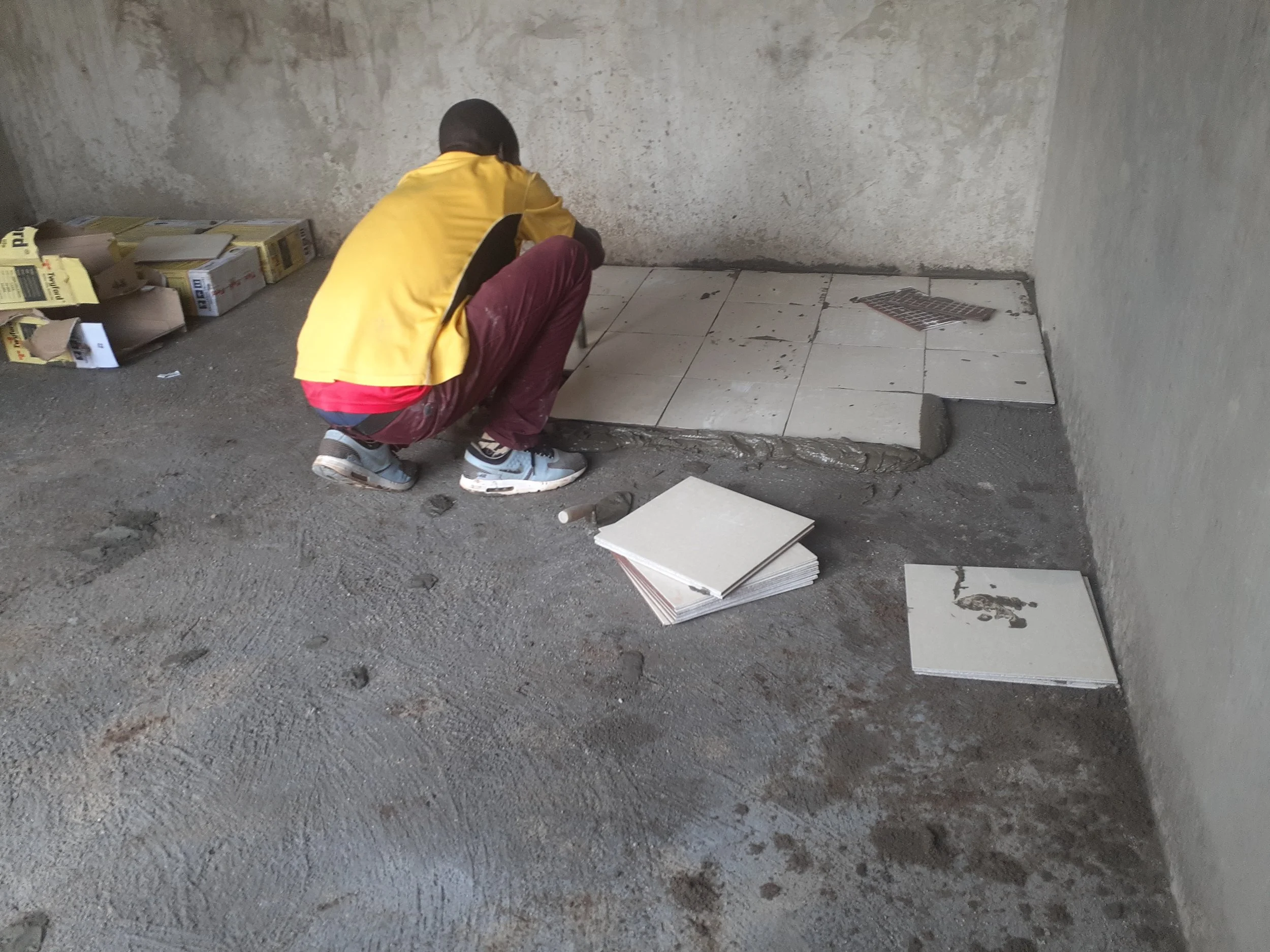  Local laborers were brought in to install the new floor tiles for the empty classroom. 