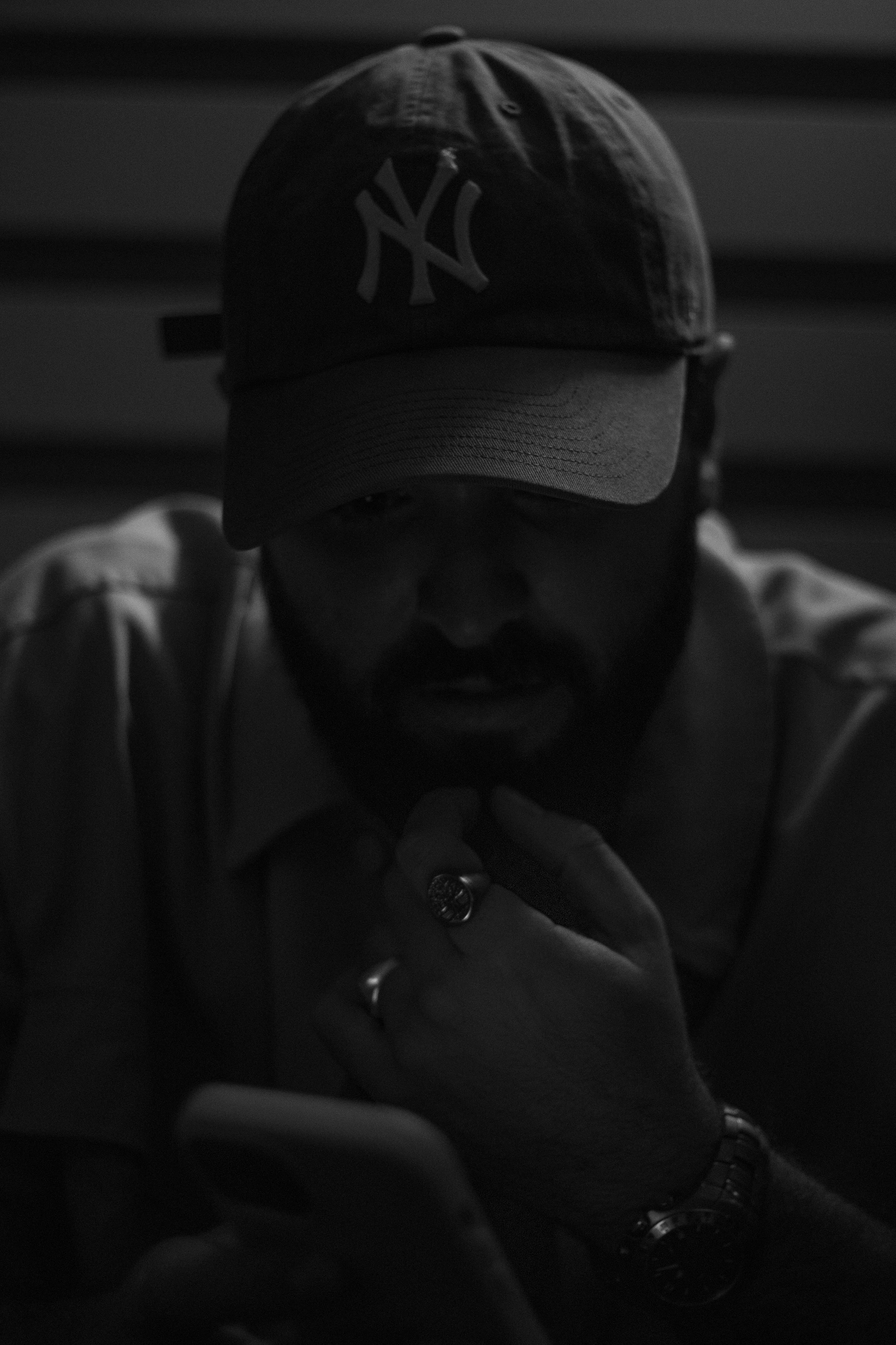 Hombre con gorra de los Yankees revisando su teléfono en un ambiente oscuro.