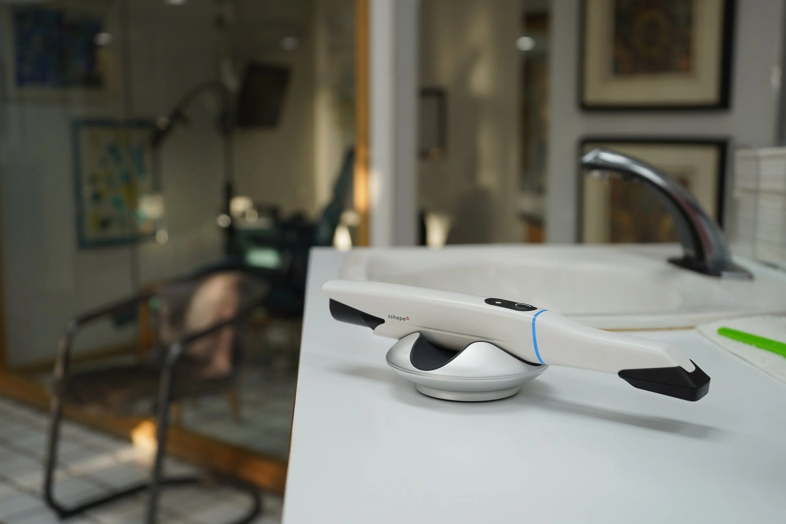 Digital thermometer placed on a white surface next to a kitchen sink in an indoor setting.