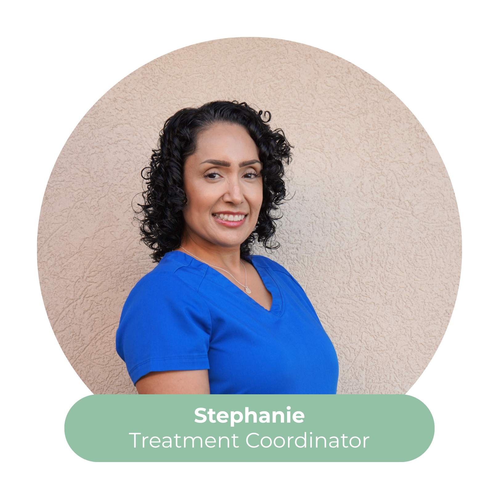 Photograph of Stephanie, a treatment coordinator, wearing a blue uniform and standing in front of a beige textured wall.