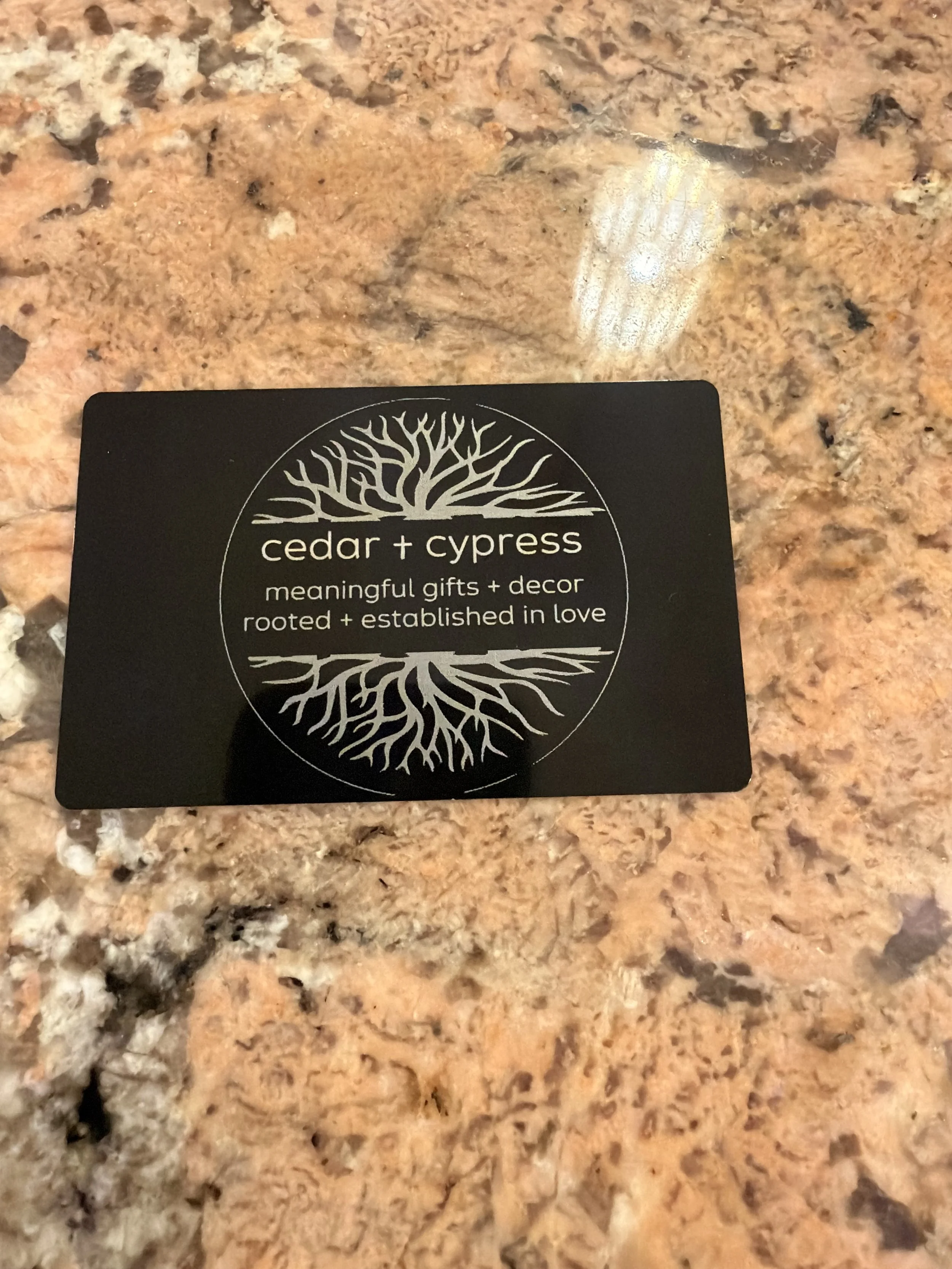 A black metal business card for Cedar + Cypress