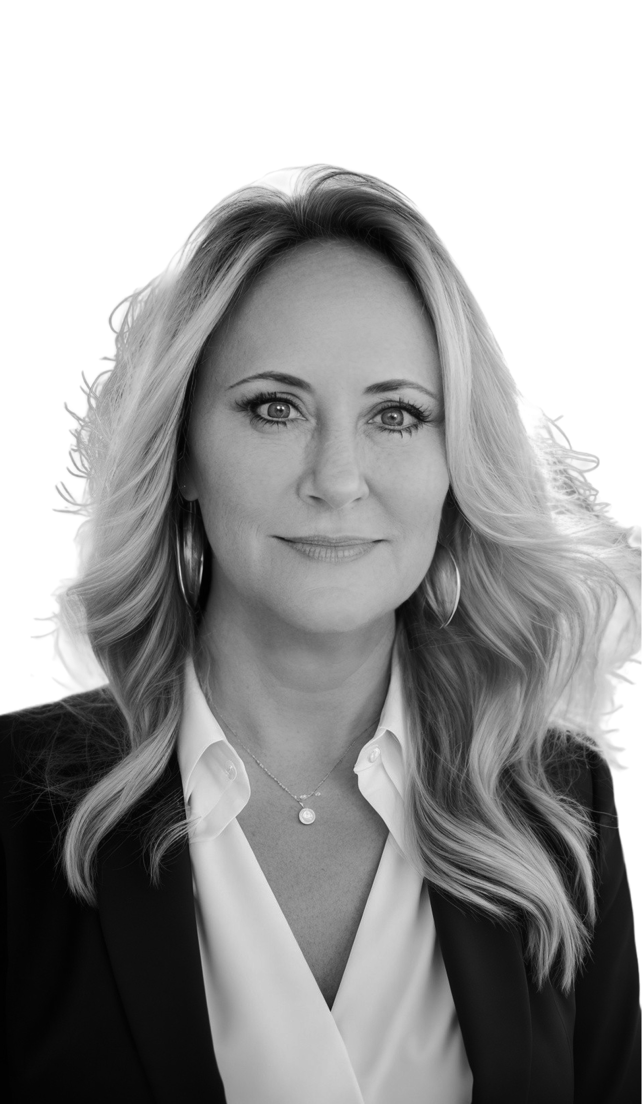 Black and white portrait of a woman with long wavy hair, wearing a white blouse and a dark blazer, looking directly at the camera with a slight smile.