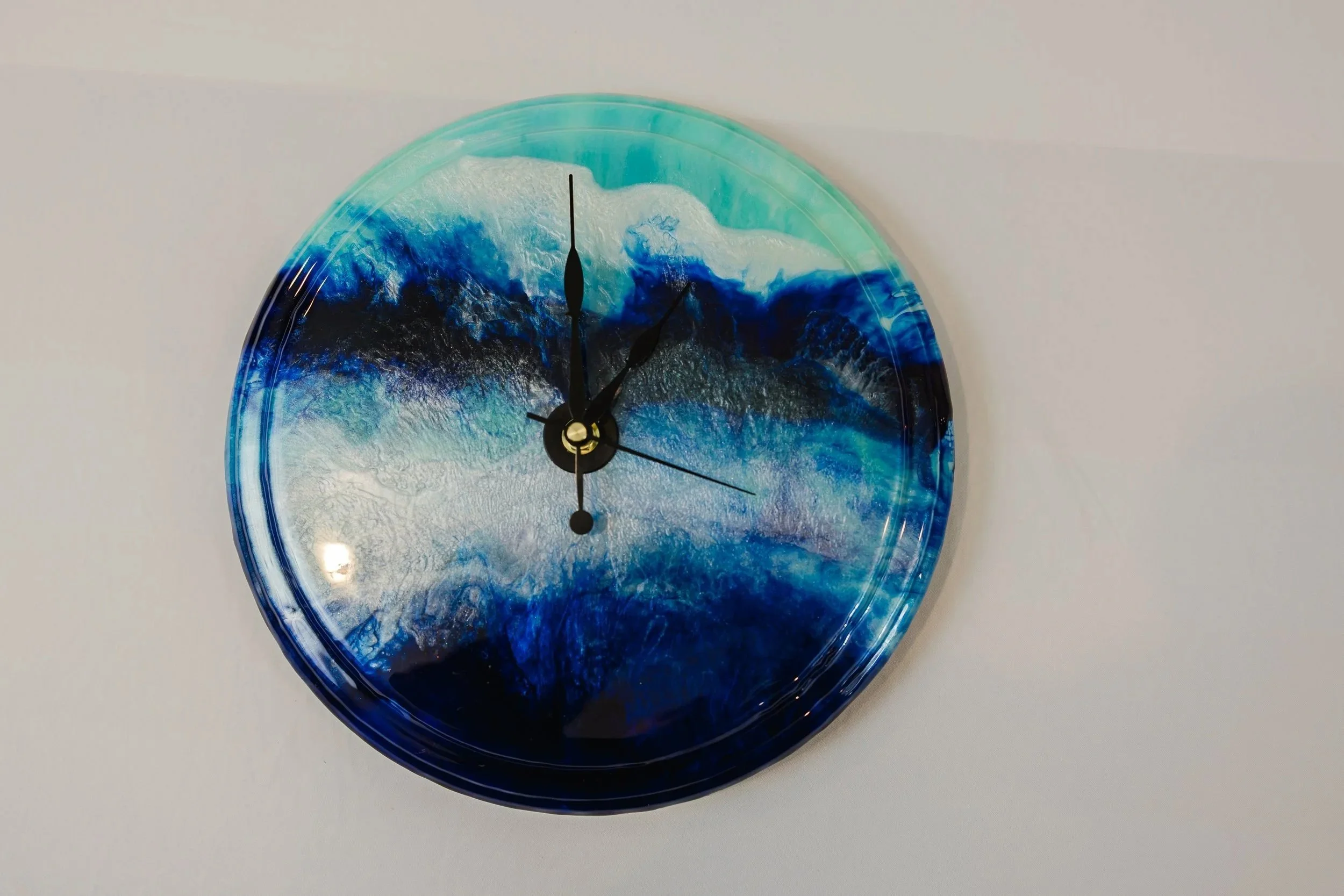 A round wall clock with a blue ocean wave design background.