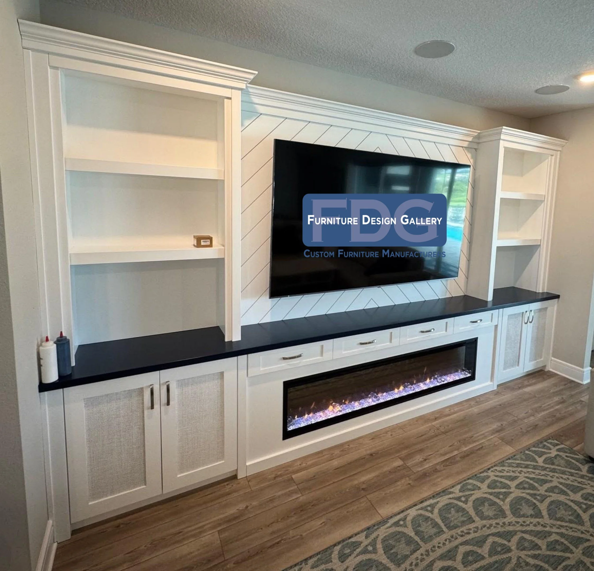 28. This sophisticated custom wall unit features a chevron-patterned TV backdrop, sleek black countertops, and mesh-front cabinetry for a modern, textured look anchored by an impressive integrated fireplace.