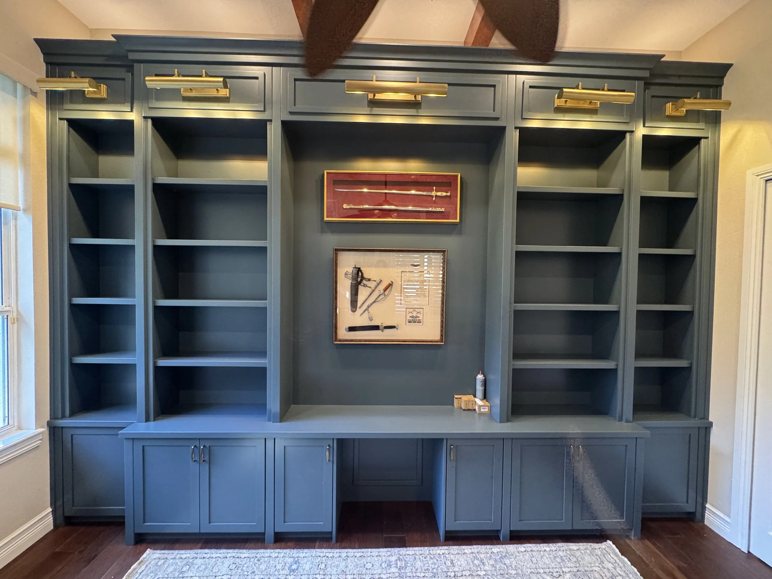 18. Sophisticated and commanding. This deep blue built-in features integrated brass picture lighting and expansive shelving for a workspace that doubles as a curated gallery.