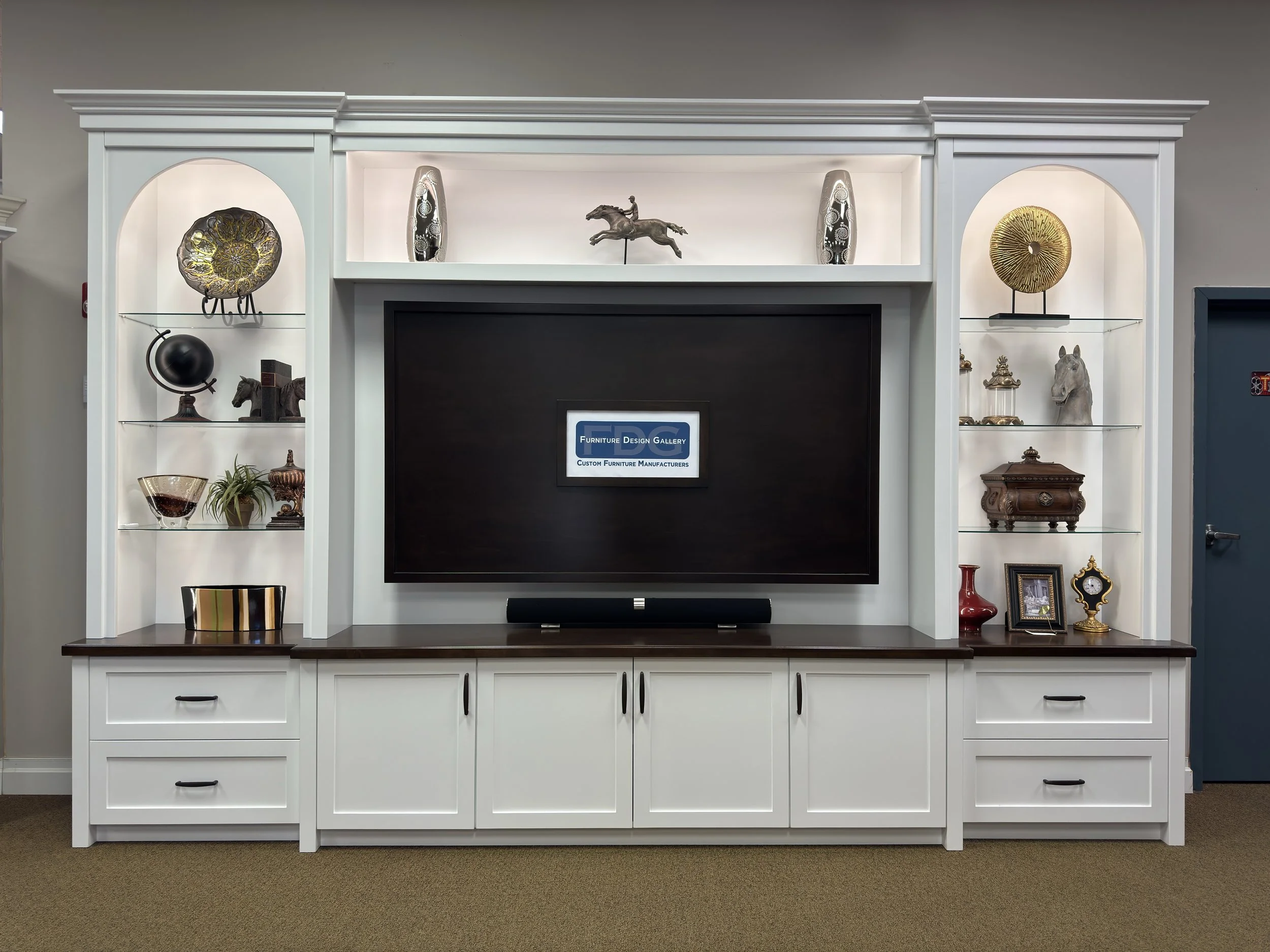 26. Timeless craftsmanship meets modern functionality in this elegant wall unit, featuring arched glass-shelf displays, integrated lighting, and a rich wood-top base for a sophisticated living room statement.