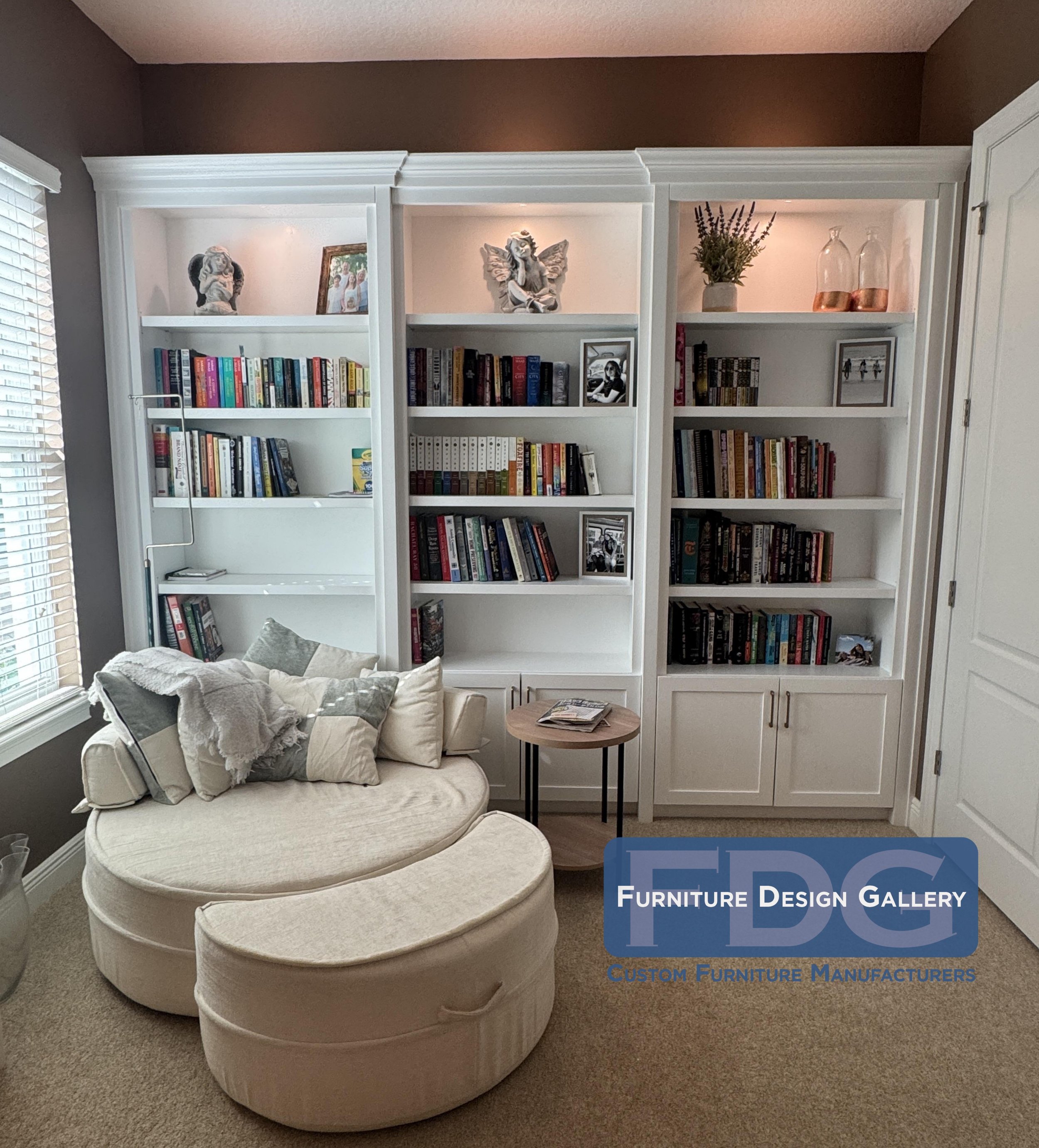 28.  Bring your dream home library to life. We designed this classic white built-in wall unit with timeless crown molding, warm top lighting, and clean lower cabinets to create the perfect cozy backdrop.
