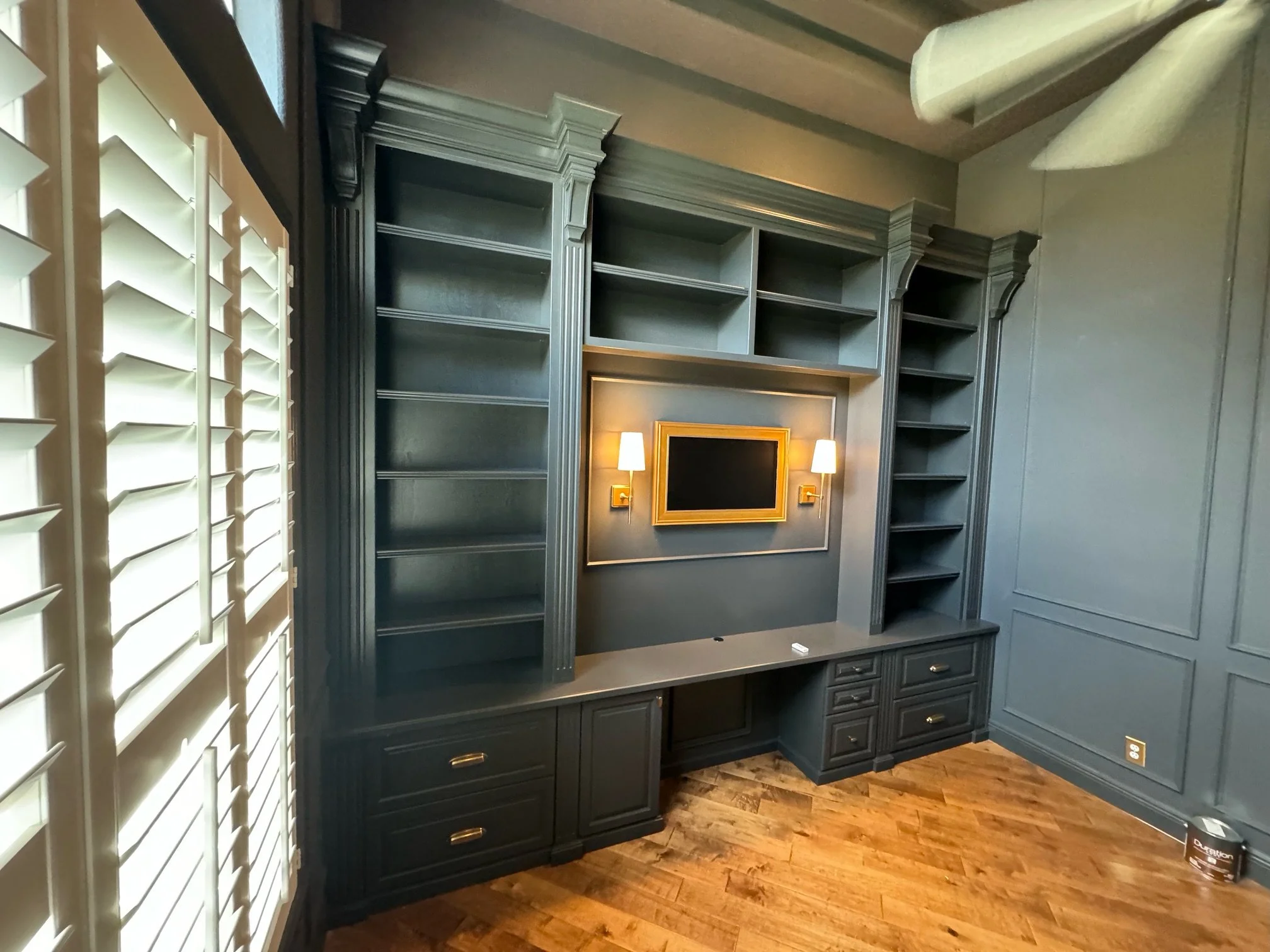 14. The ultimate executive retreat. This custom painted library suite features shelving, elegant brass sconce lighting, and a built-in workspace, all finished with sophisticated picture frame molding for a timeless, professional look.