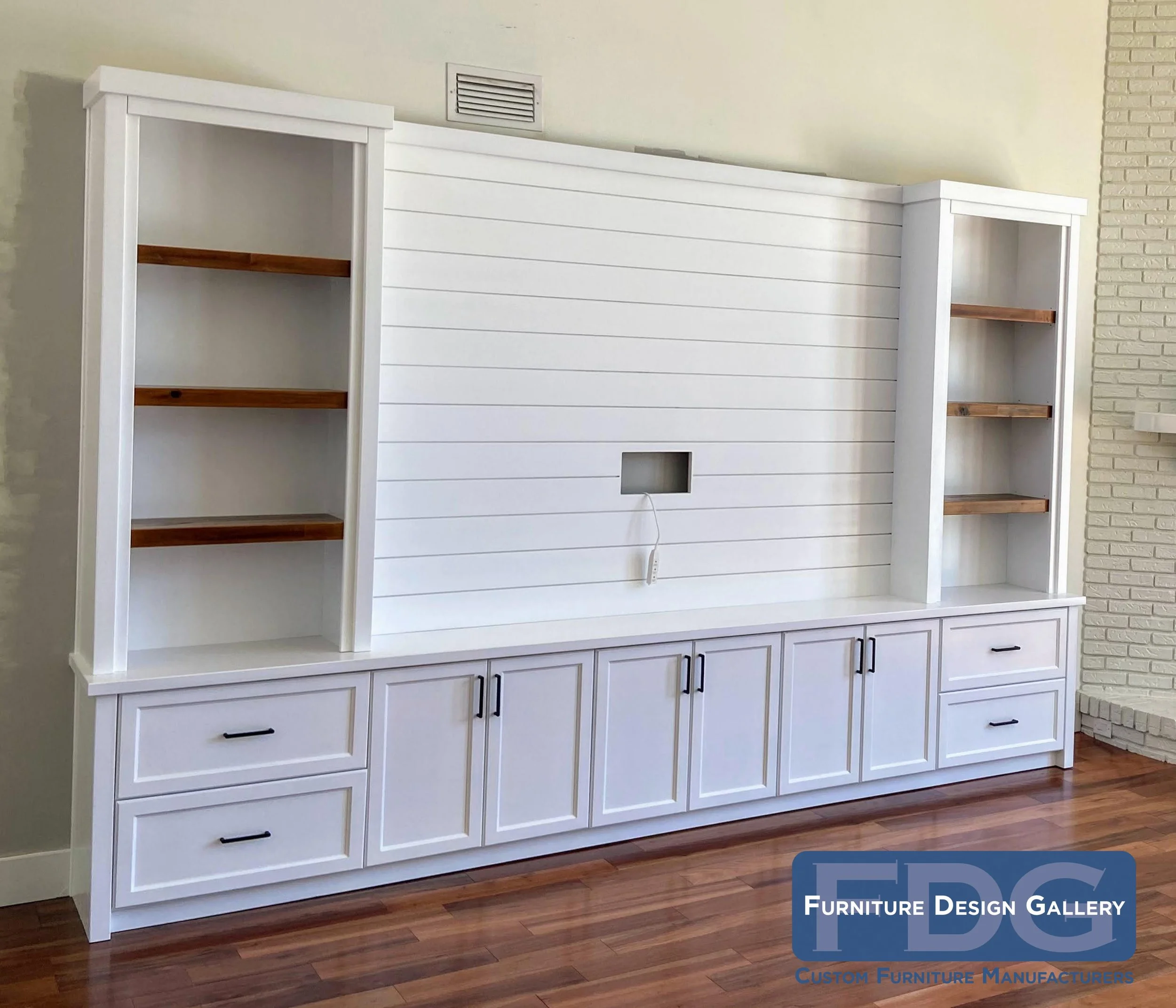 70. Brighten up your living space with this custom shiplap entertainment center. The crisp white cabinetry and sleek black hardware pair beautifully with warm, stained wood shelving to create plenty of storage and style.