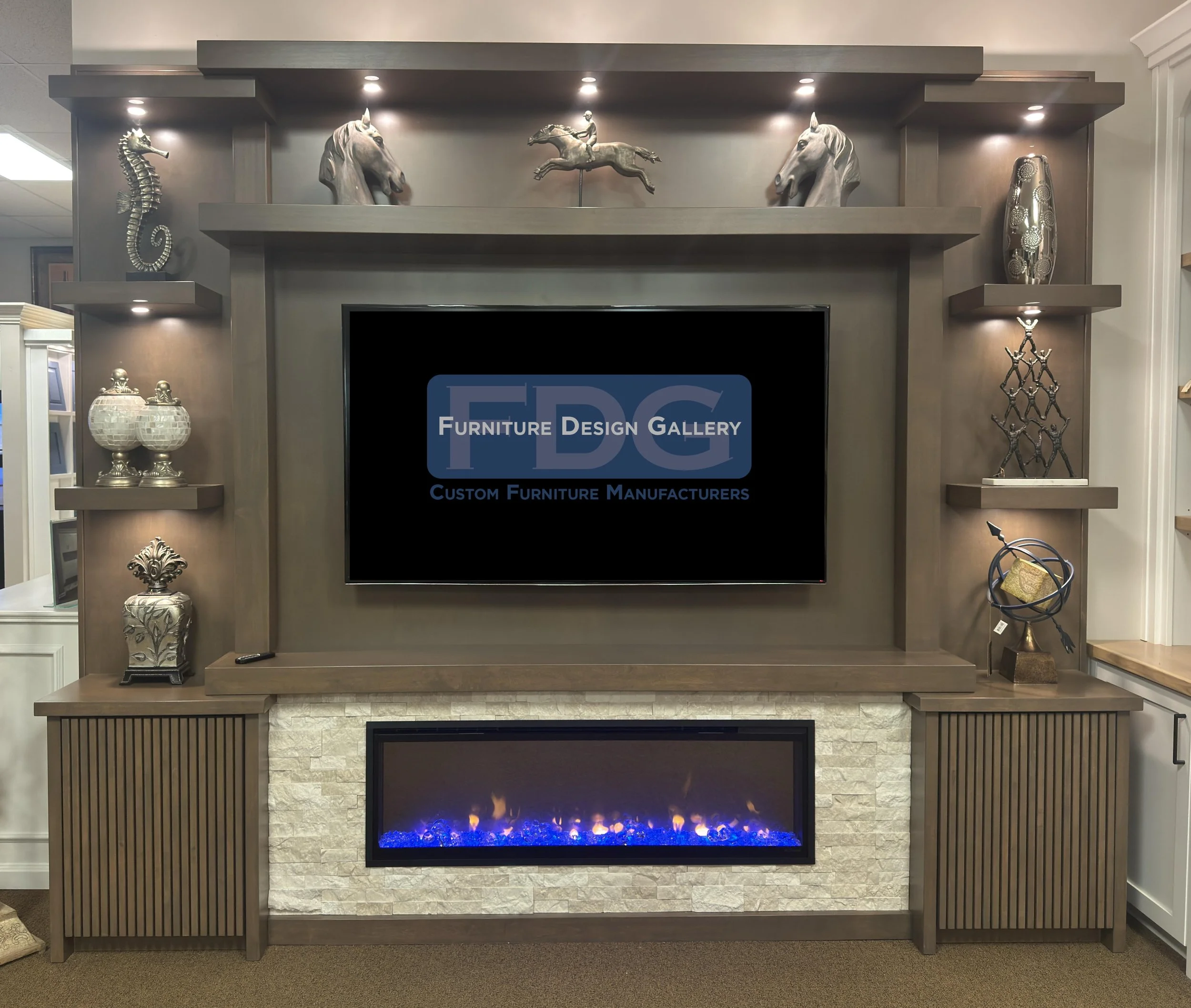 10. Artistry meets ambiance. This custom wall unit features tiered floating shelves with integrated spotlighting, textured stone accents, and slatted cabinetry for a look that’s as sophisticated as it is cozy.
