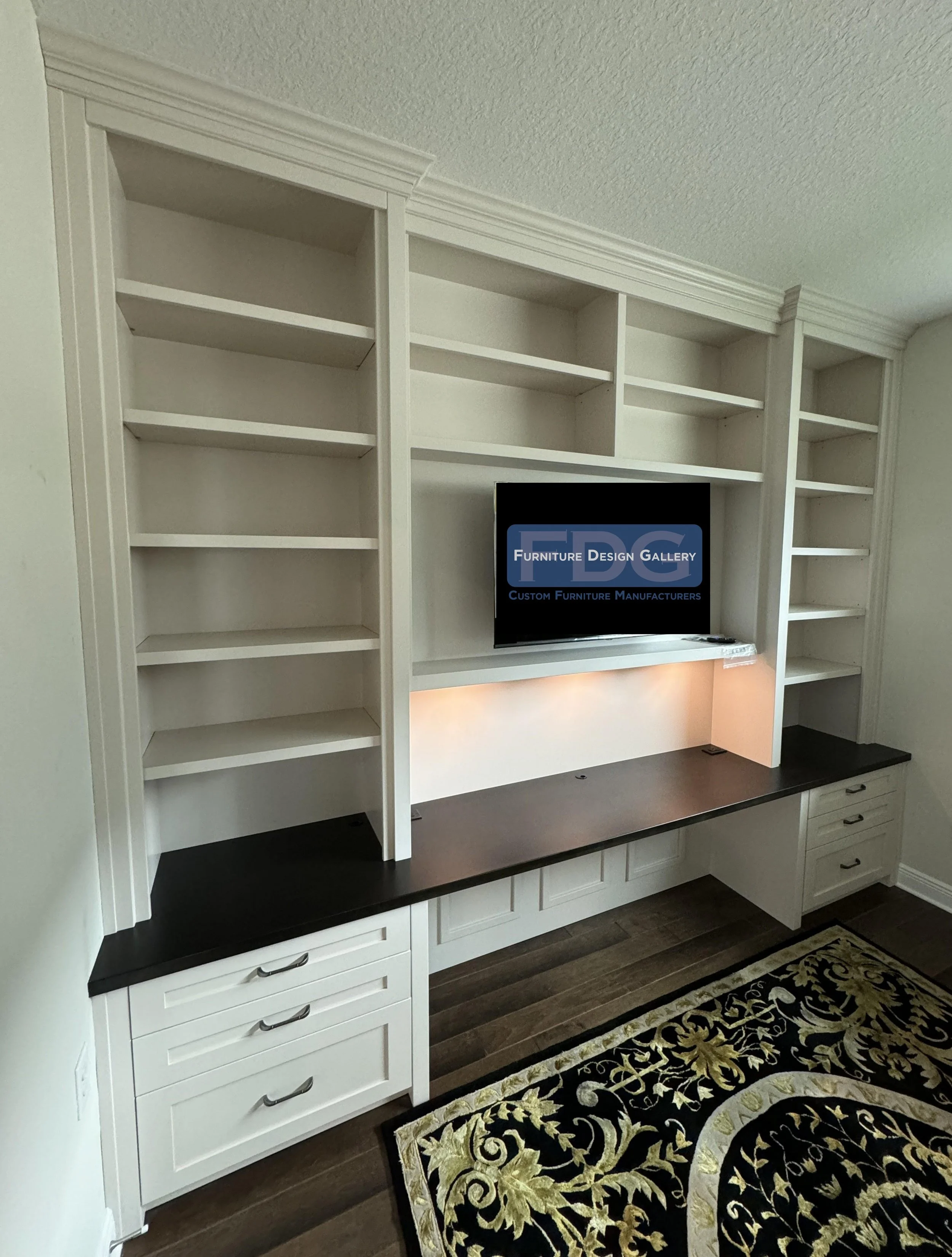 13. Streamlined and productive. This custom wall-to-wall office unit features extensive open shelving, a sleek dark-stained desktop, and warm integrated lighting for an elevated, functional workspace.