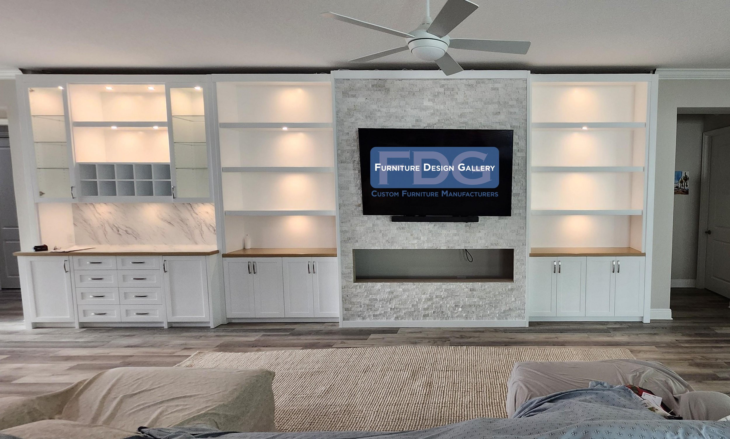 65.  Bring your living room to life with a custom entertainment wall built for hosting. This seamless design pairs a textured stone media center with an integrated home bar, warm LED lighting, and natural wood countertops.