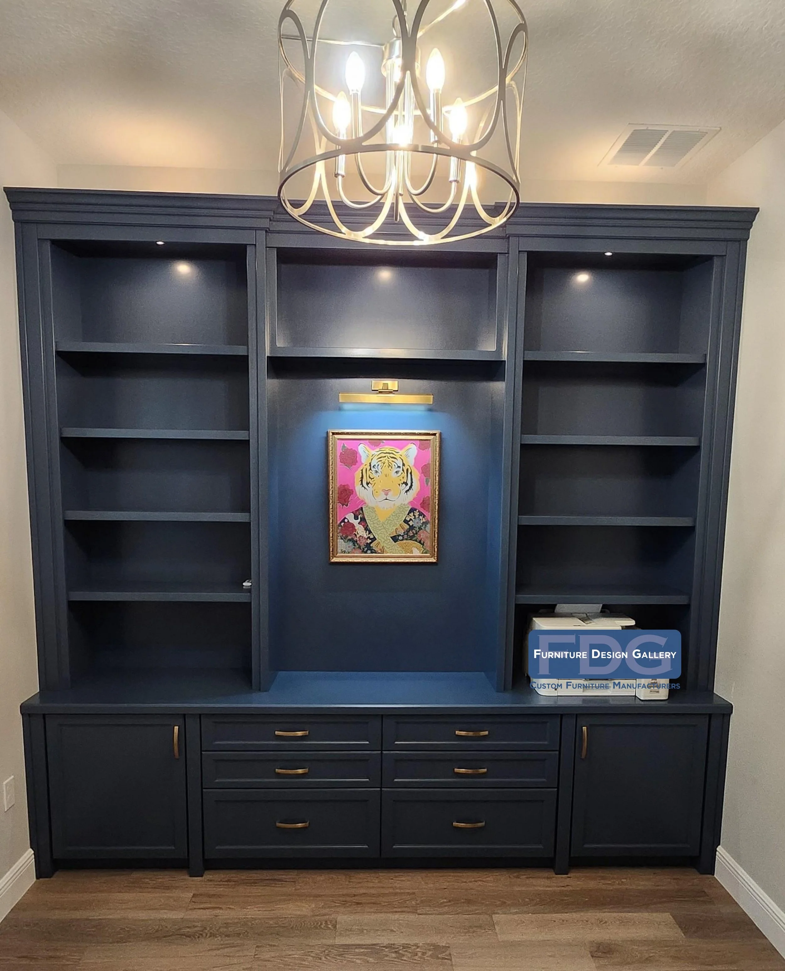 22.  Bold color meets custom storage. This deep blue built-in features spacious open shelving, lower drawers and cabinets with gold hardware, and a dedicated center display nook complete with built-in picture lighting.