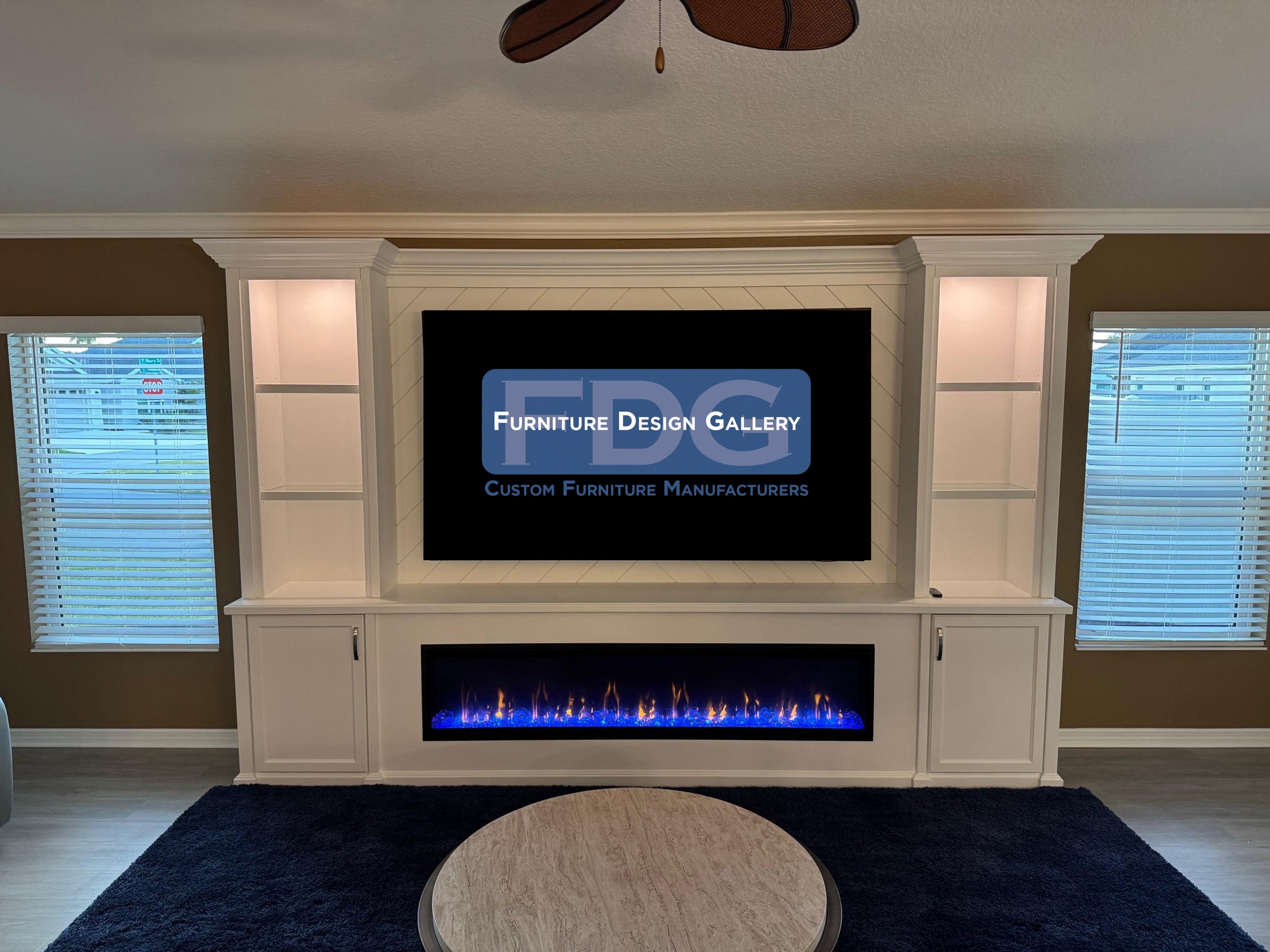 68. Transform your living room with a custom entertainment center that blends classic details and modern features. This bright white unit showcases a striking chevron accent backdrop, integrated glass shelving with puck lighting, and an expansive lin