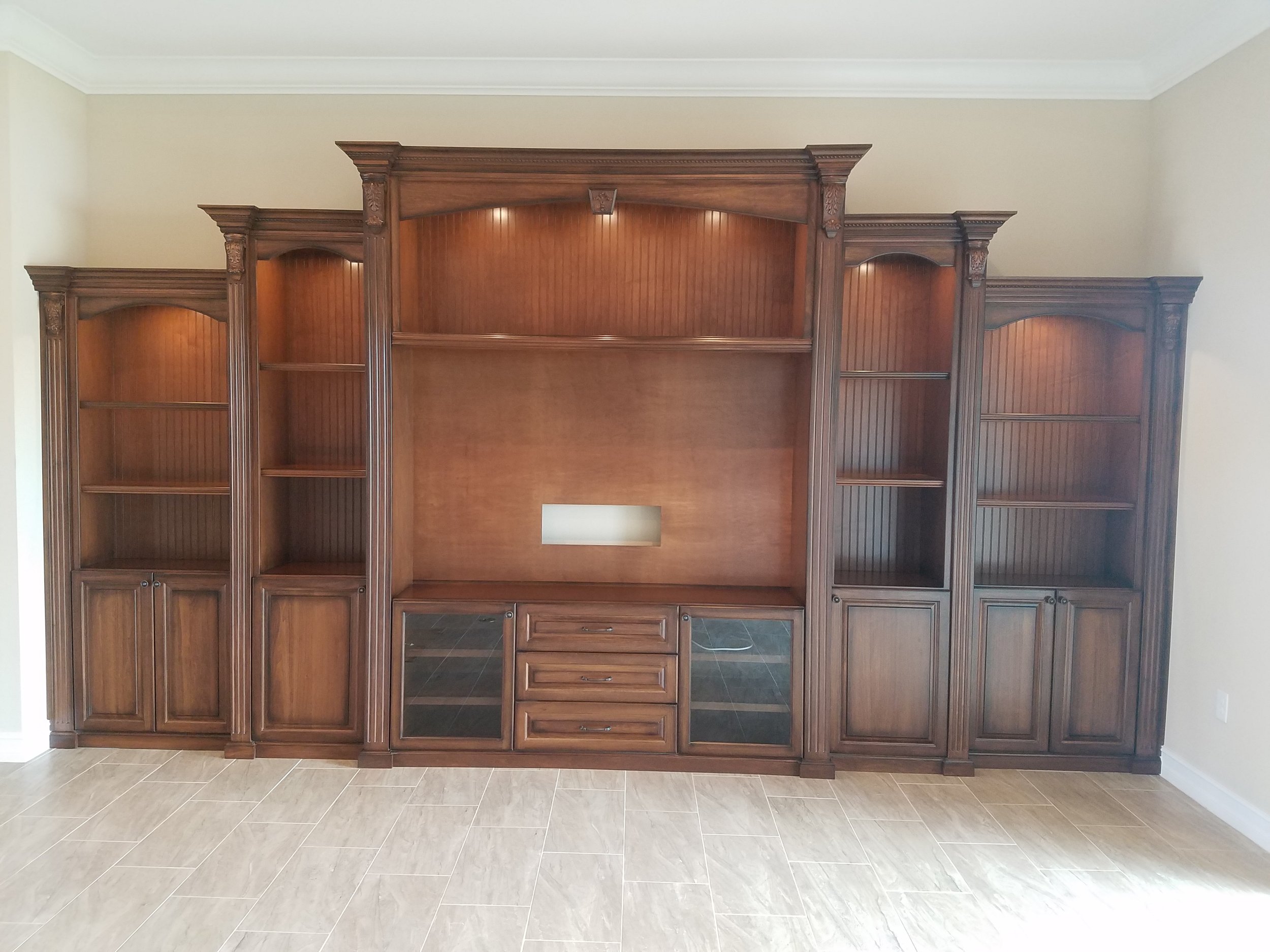 4. A masterpiece of traditional craftsmanship. This tiered wood wall unit showcases rich cherry tones, elegant fluted columns, and arched lit niches, offering a sophisticated focal point for a grand living room or library.