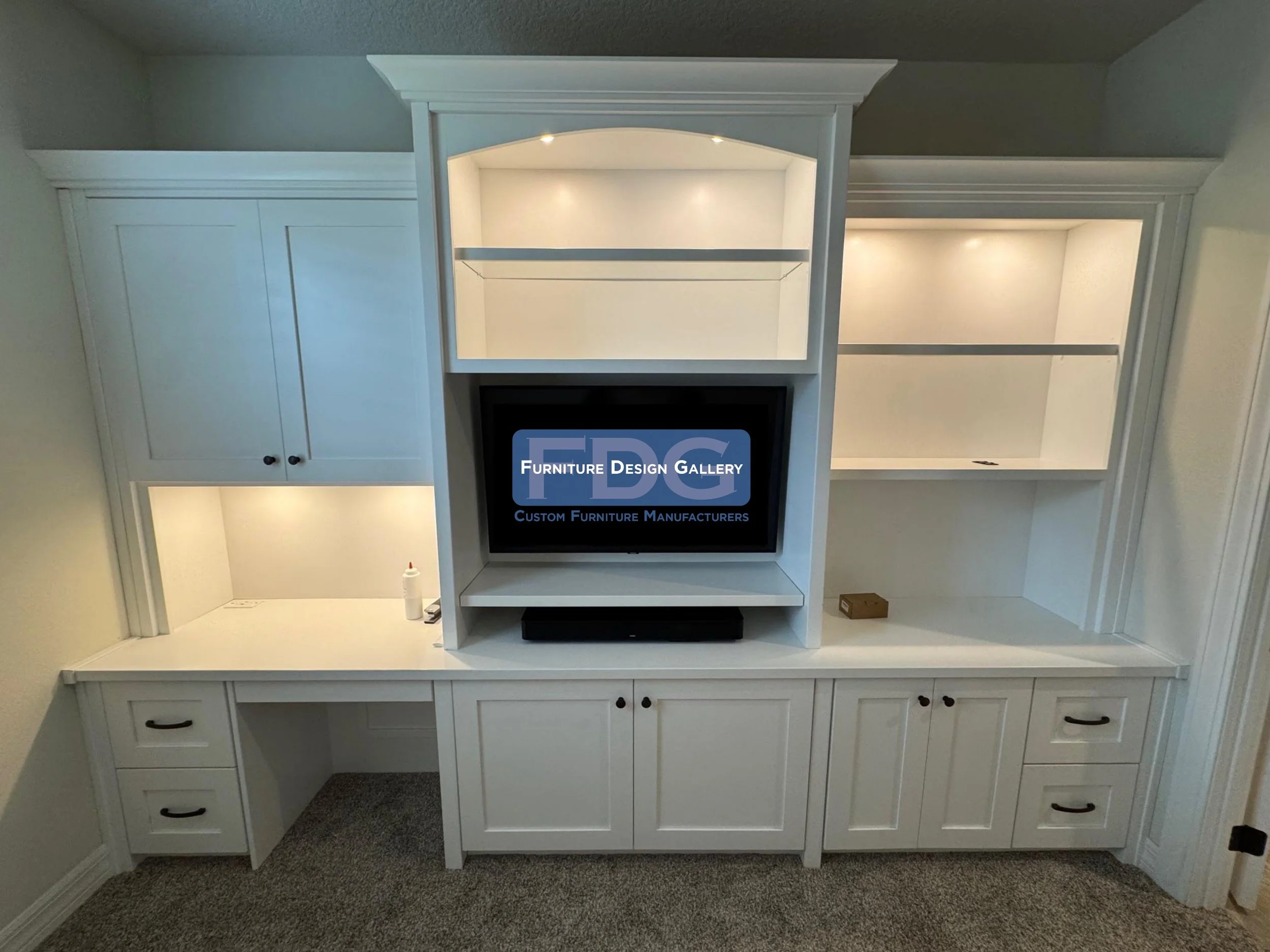12. Versatile and refined. This custom white wall unit seamlessly combines a dedicated workspace with a media center, featuring elegant arched detailing, glass shelving, and integrated lighting for a clean, cohesive look.