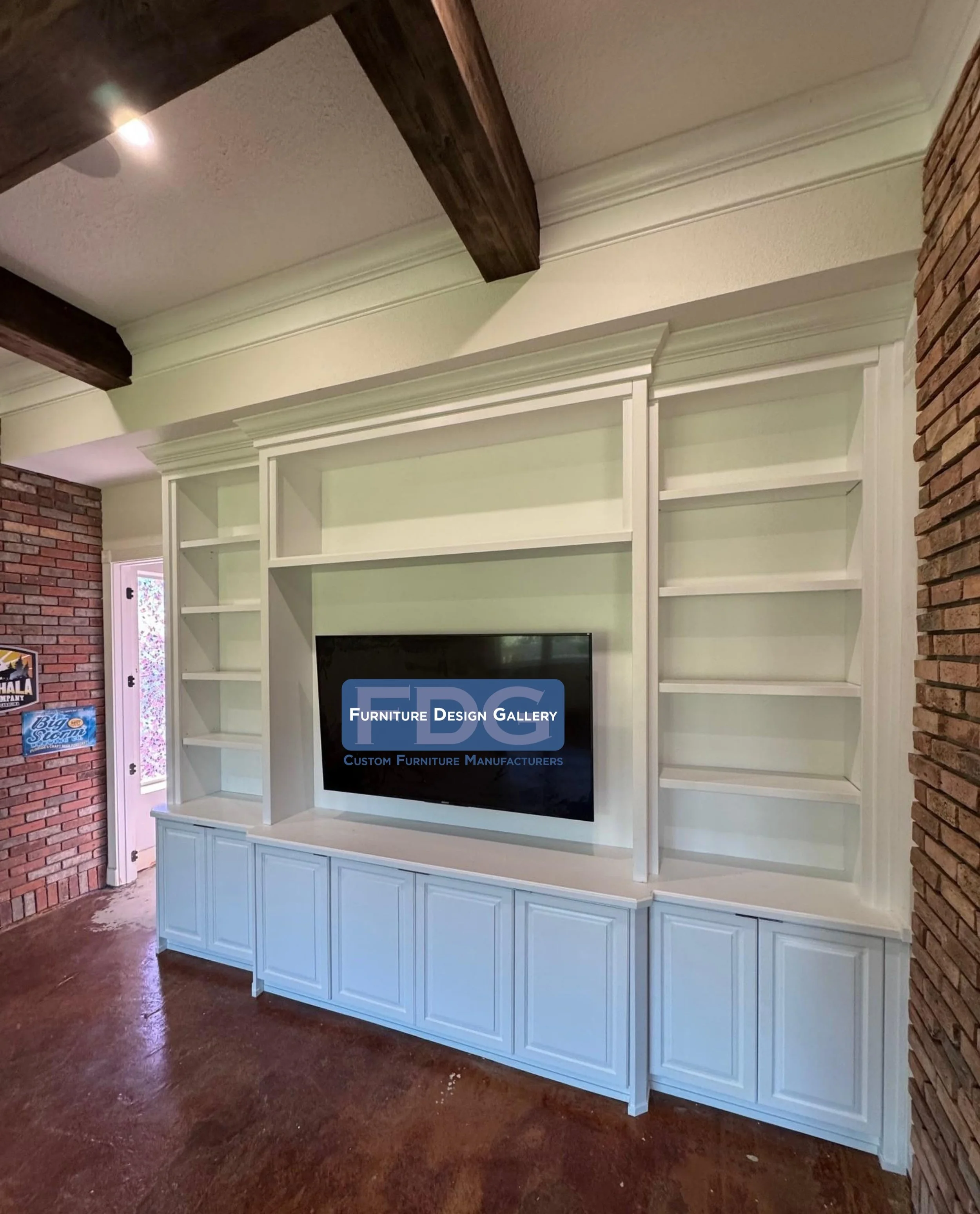 60. This custom-built entertainment center with detailed cabinetry and extensive shelving perfectly complements the rustic exposed brick and wood beams. Tailored for style and function.