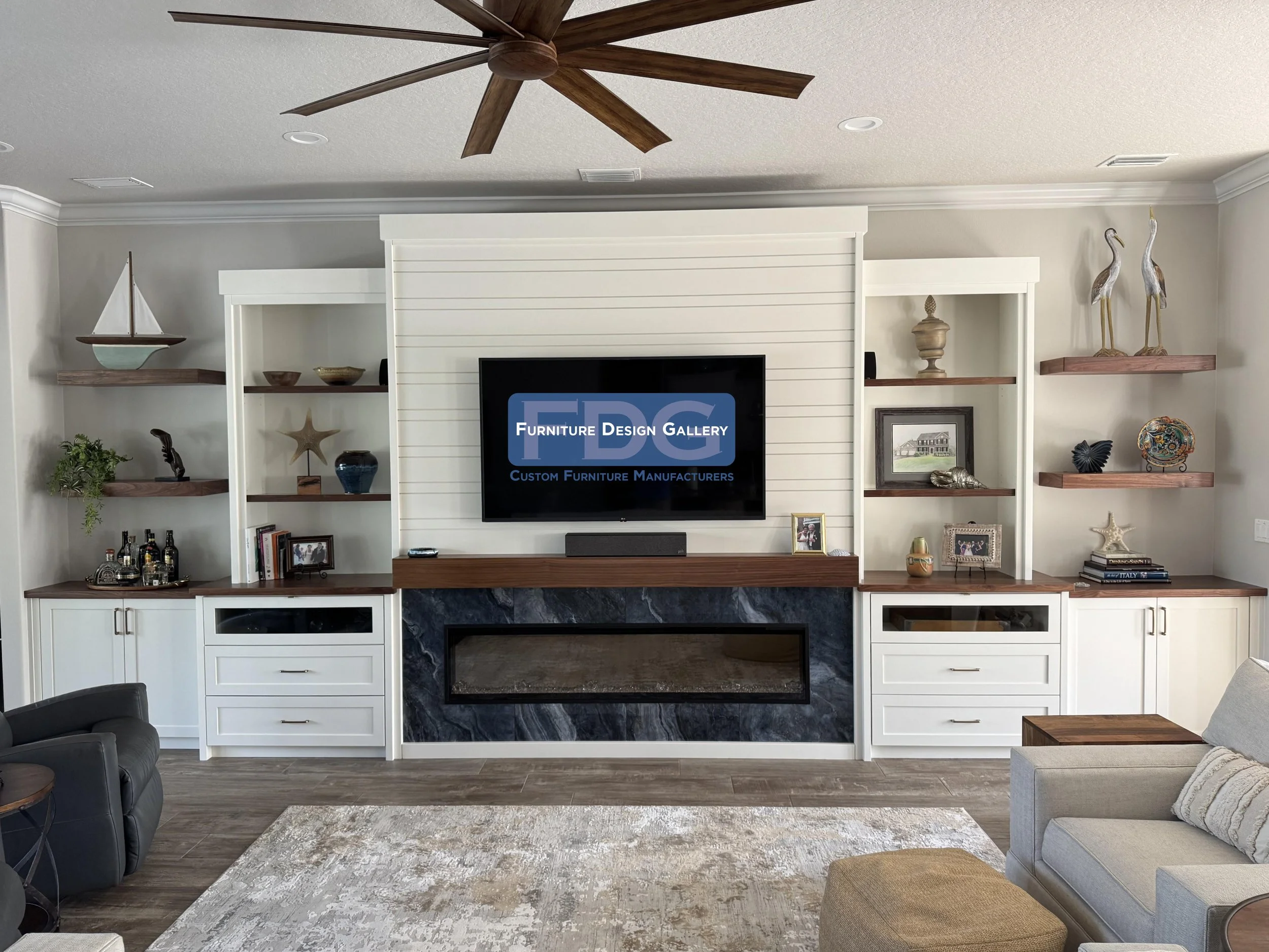 75.  Upgrade your living space with an expansive custom media wall designed for entertainment and display. This stunning piece pairs a clean shiplap backdrop and rich wood countertops with an integrated linear fireplace framed by dark marble-style ti