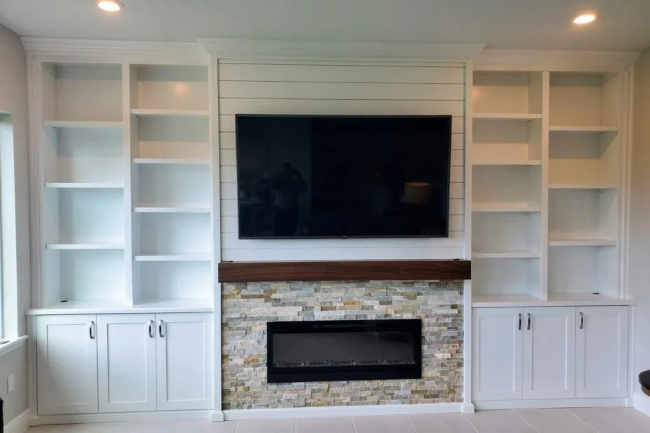 16. A masterclass in texture. This custom built-in combines clean white shiplap and symmetrical shelving with a natural stone fireplace and a rich walnut mantle for a look that is both cozy and contemporary.