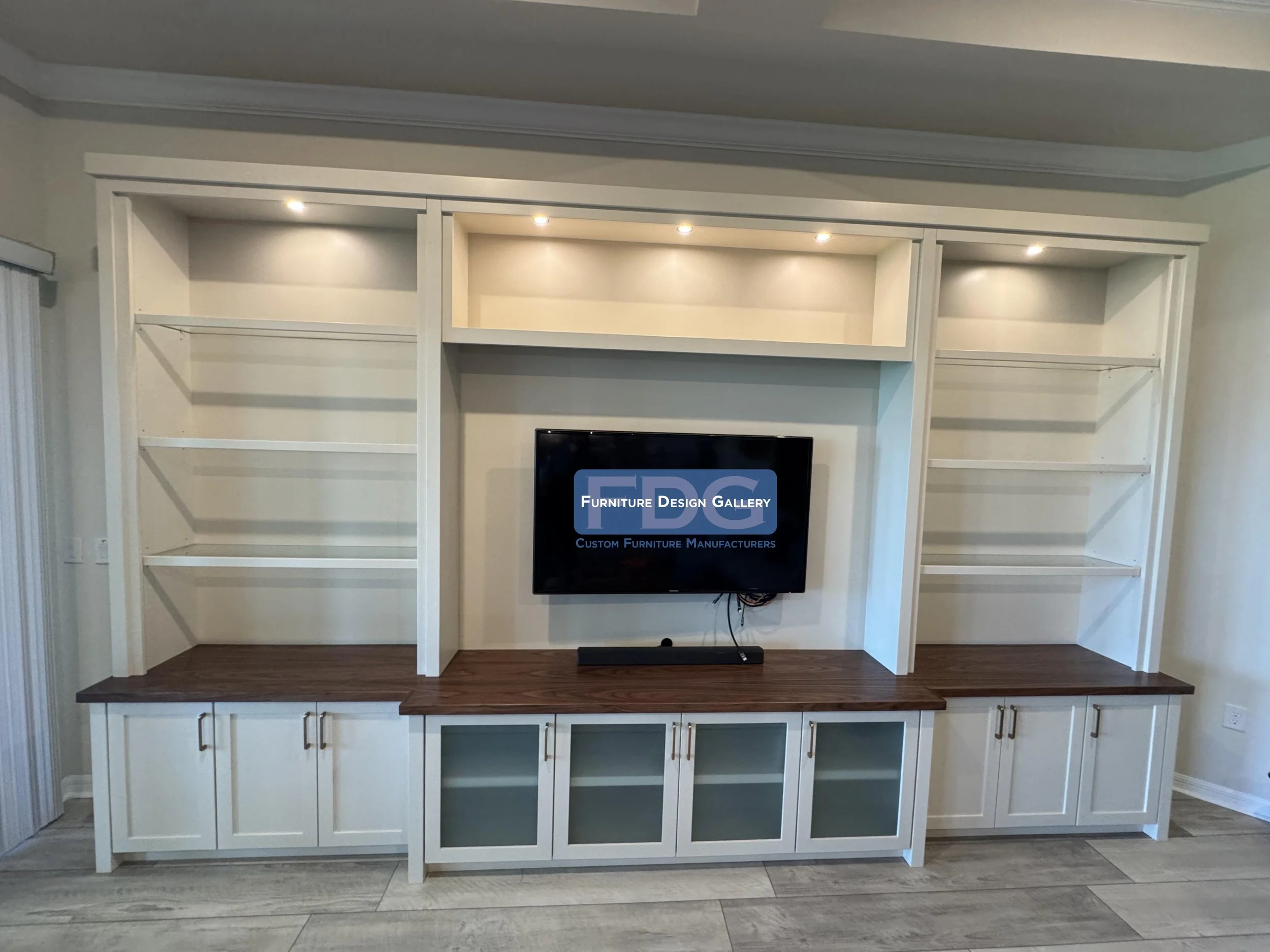 61. This custom entertainment center features a stunning dark wood countertop paired with crisp white cabinetry and frosted glass doors. The perfect modern update for any living space.