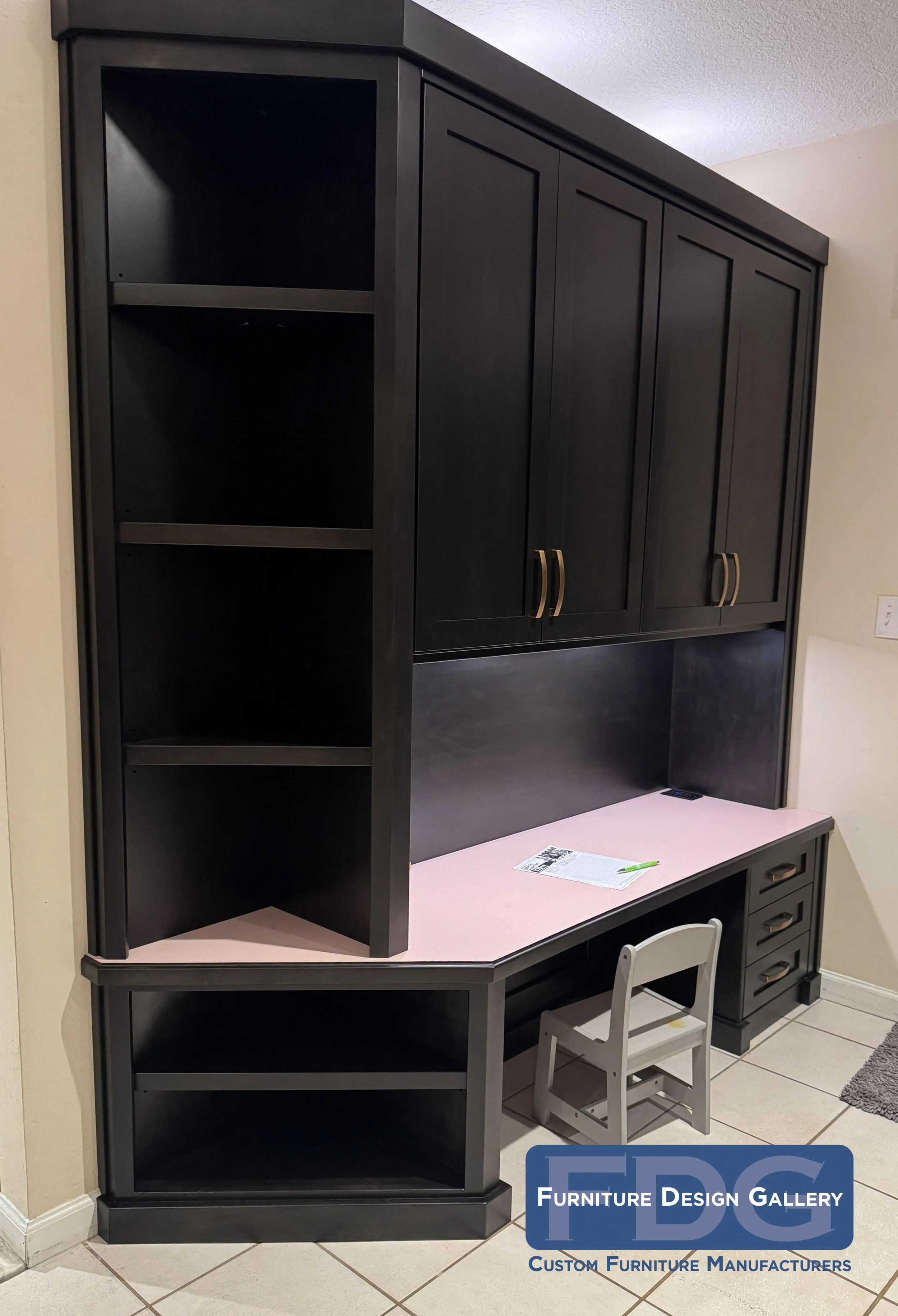 27. The perfect custom study nook. We paired deep-toned cabinetry and brass accents with a playful pink work surface, combining closed upper storage, lower drawers, and open display shelves.