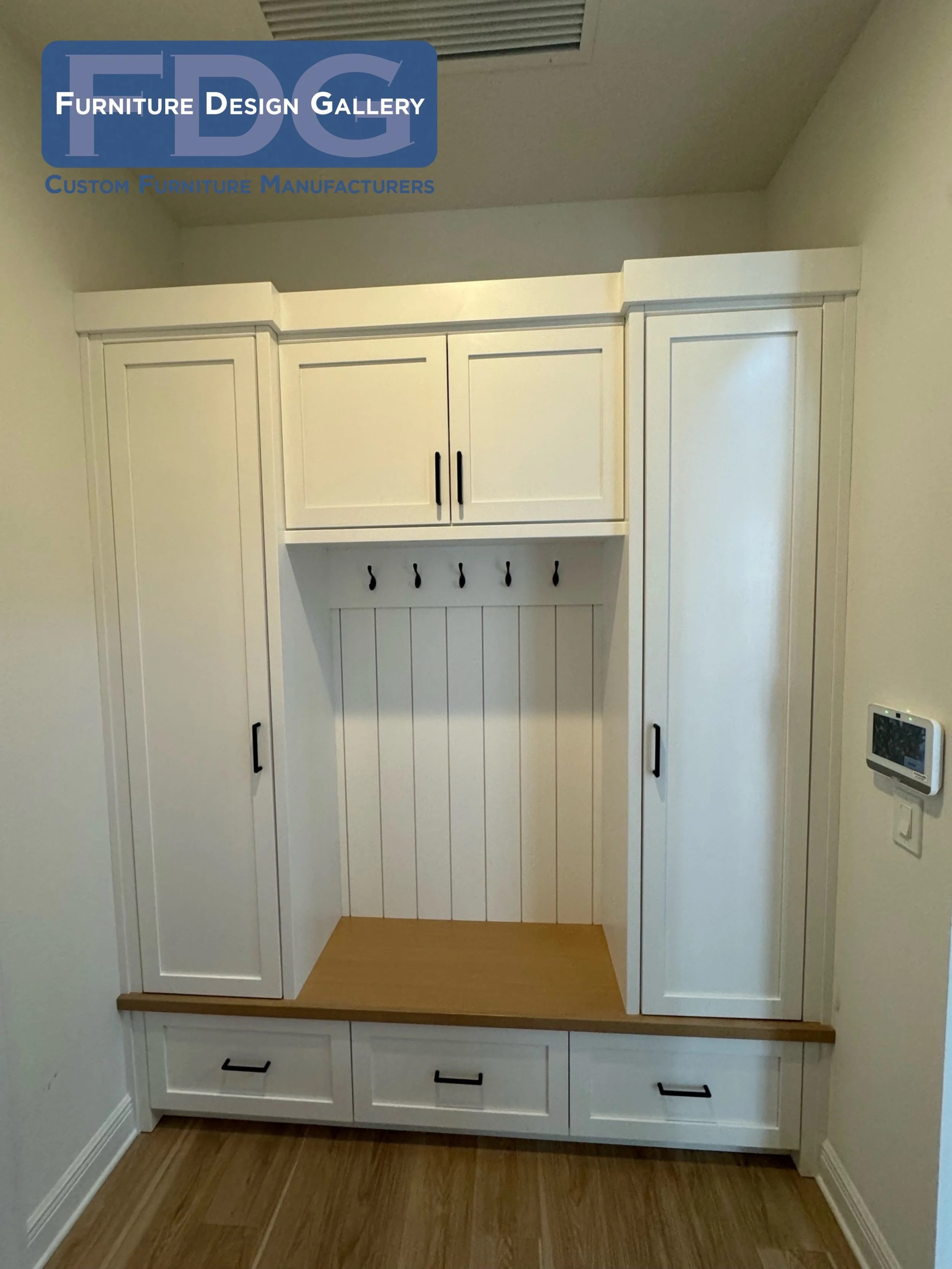 4. Ultimate organization from floor to ceiling. 🧥🧺 This symmetrical custom mudroom unit features towering side utility cabinets, overhead cupboards, and deep lower drawers to store it all, plus a warm wood bench.