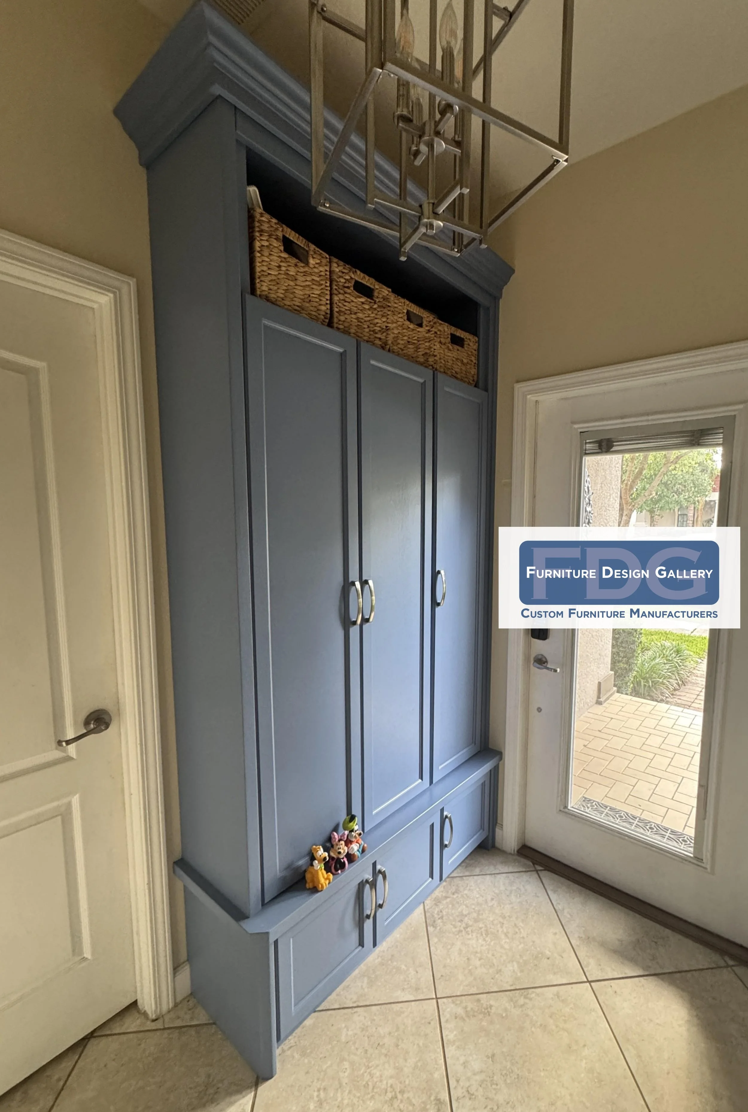 7.  Custom slate blue entryway cabinet combining integrated seating, hidden bottom drawers, and enclosed storage to maximize drop-zone organization.