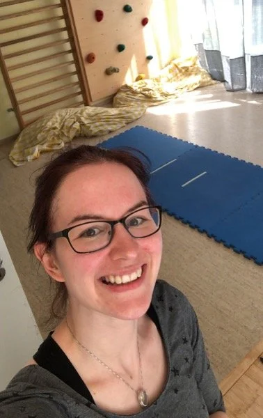 Ein Mann macht ein Selfie in einem Raum mit einer blauen Turnmatte und einer Kletterwand im Hintergrund.