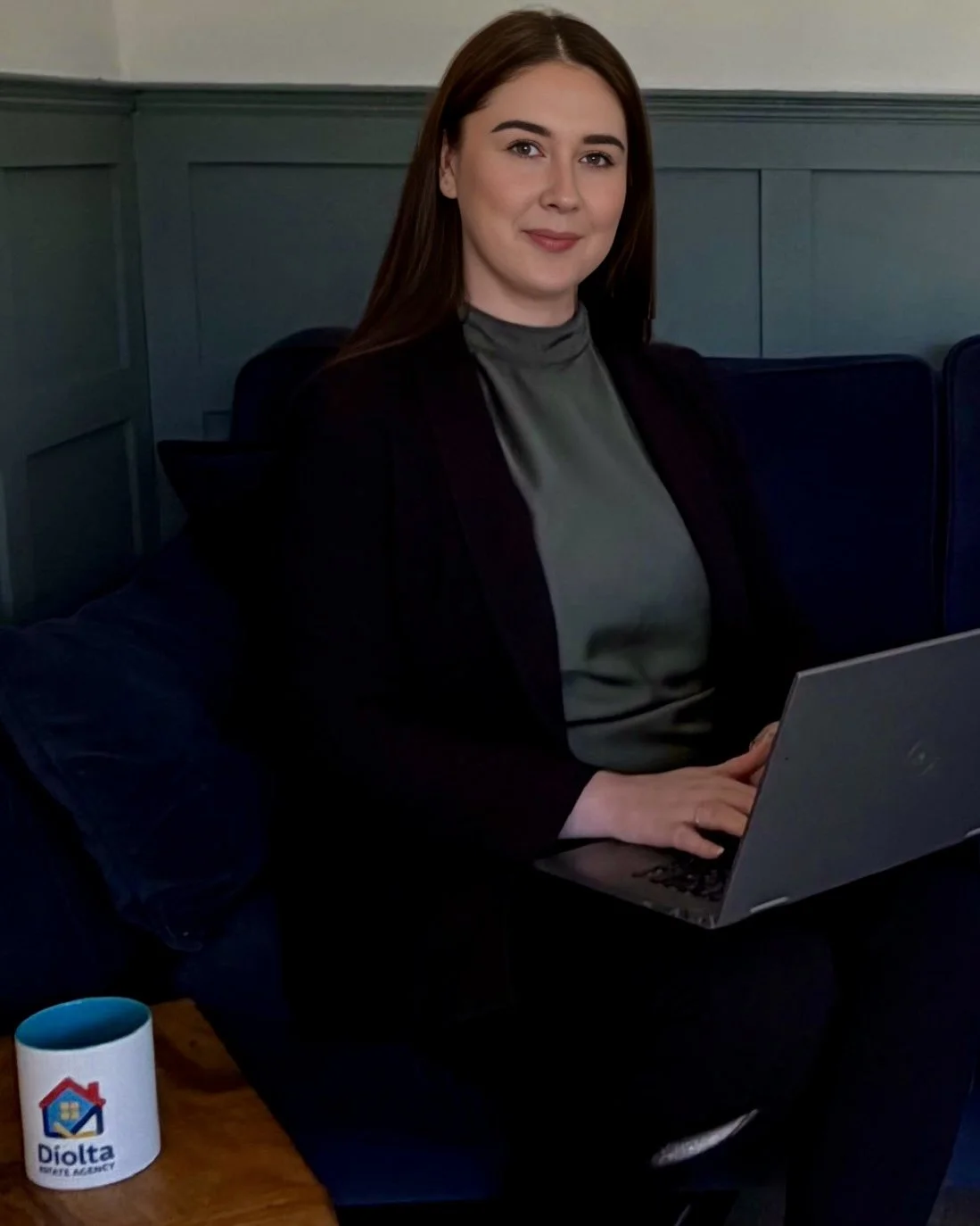 Shauna Byrne, Estate Agent, wearing a black suit and green silk blouse, smiling at the camera