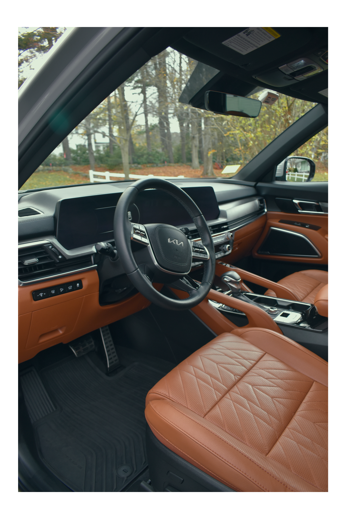 Interior of a modern Kia vehicle showroom with leather seats, steering wheel, dashboard, and gear shift visible