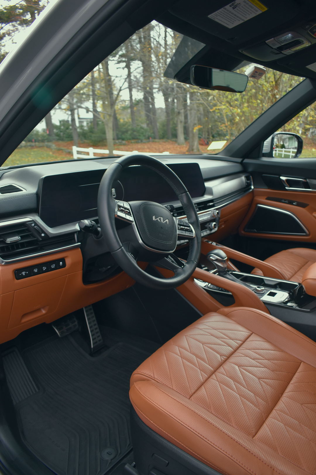 Interior of a modern Kia vehicle showroom with leather seats, steering wheel, dashboard, and gear shift visible