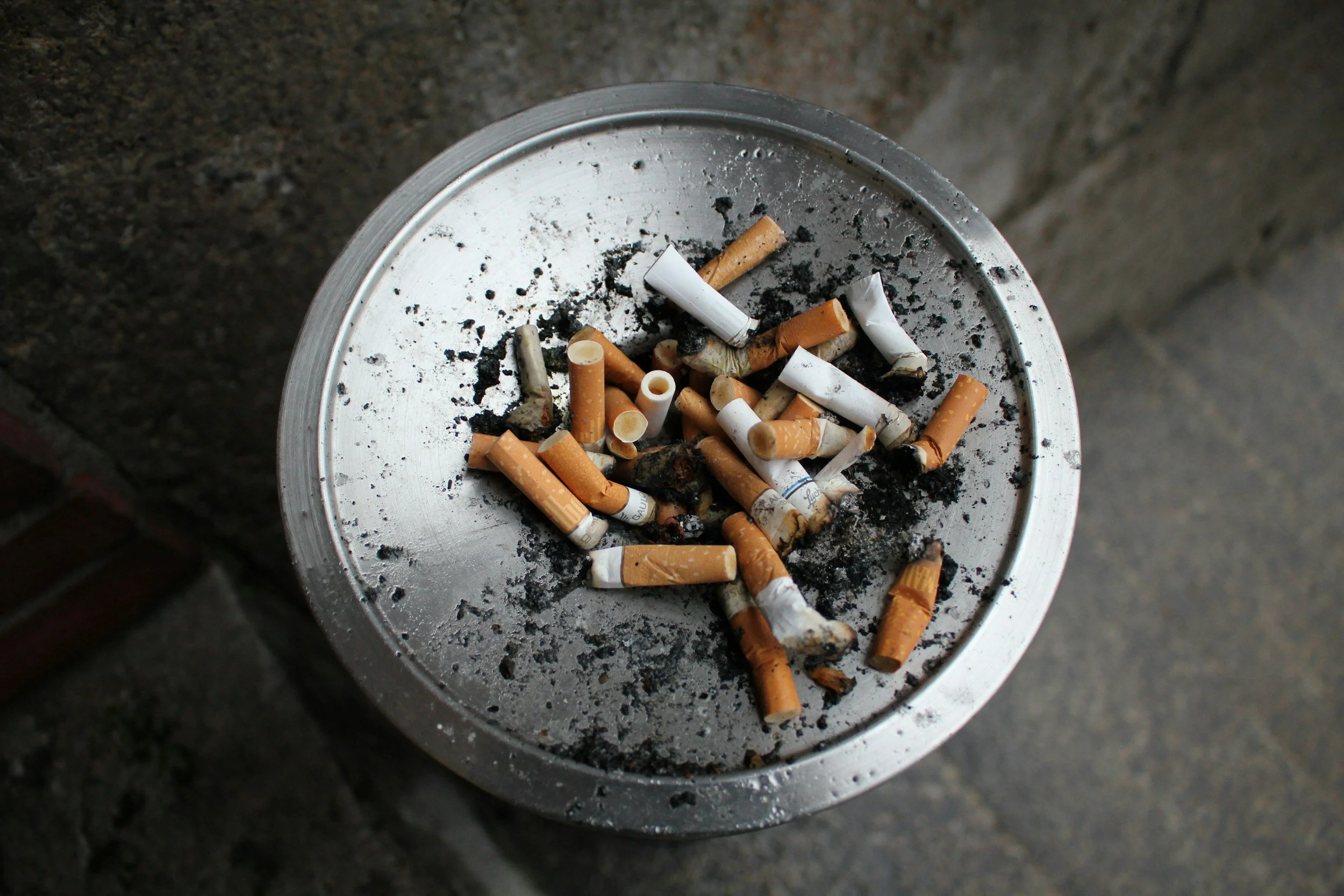 Cendre et mégots de cigarettes sur un cendrier en métal