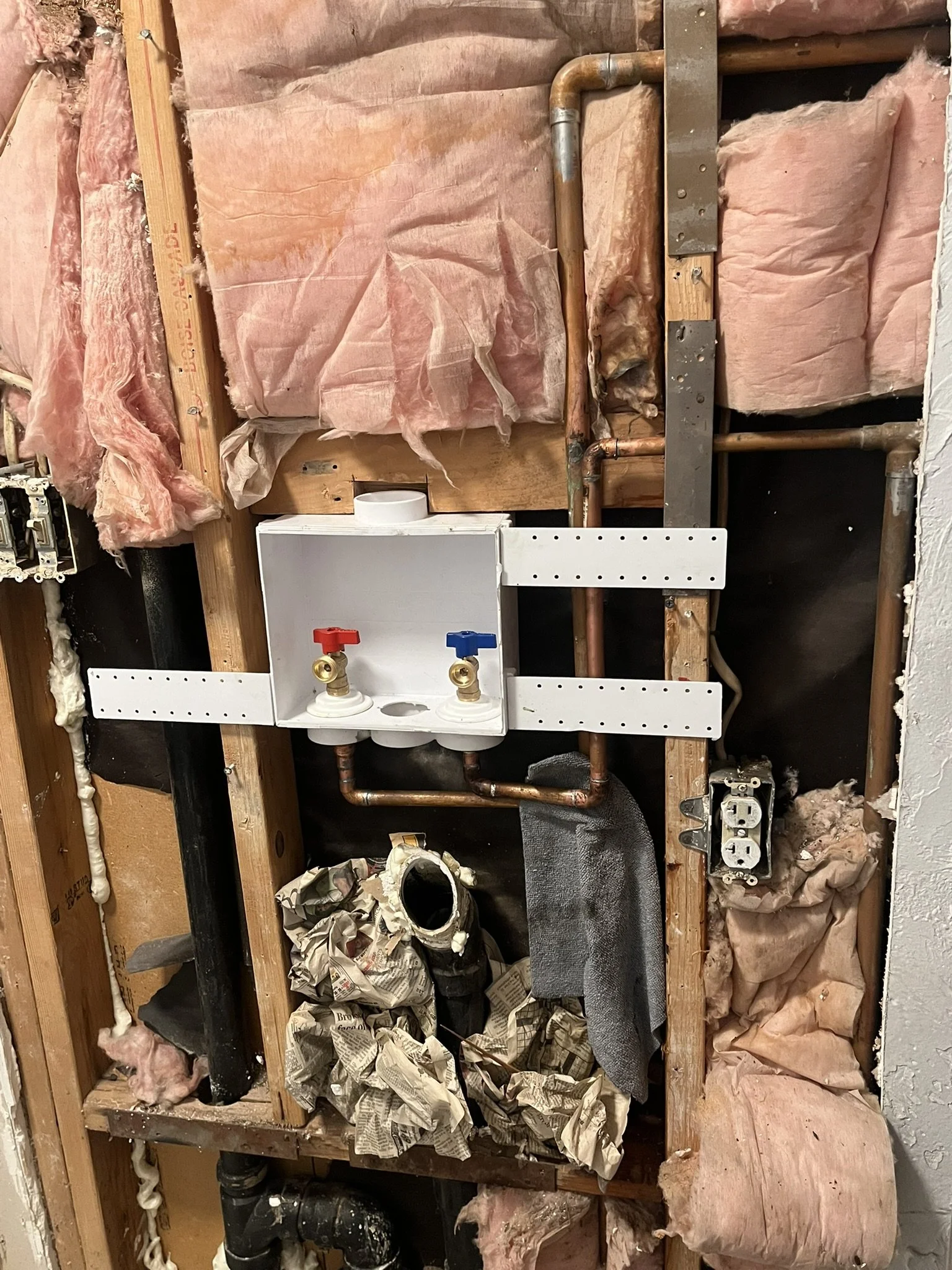 Plumbing setup with copper pipes, a white enclosure with red and blue water valve