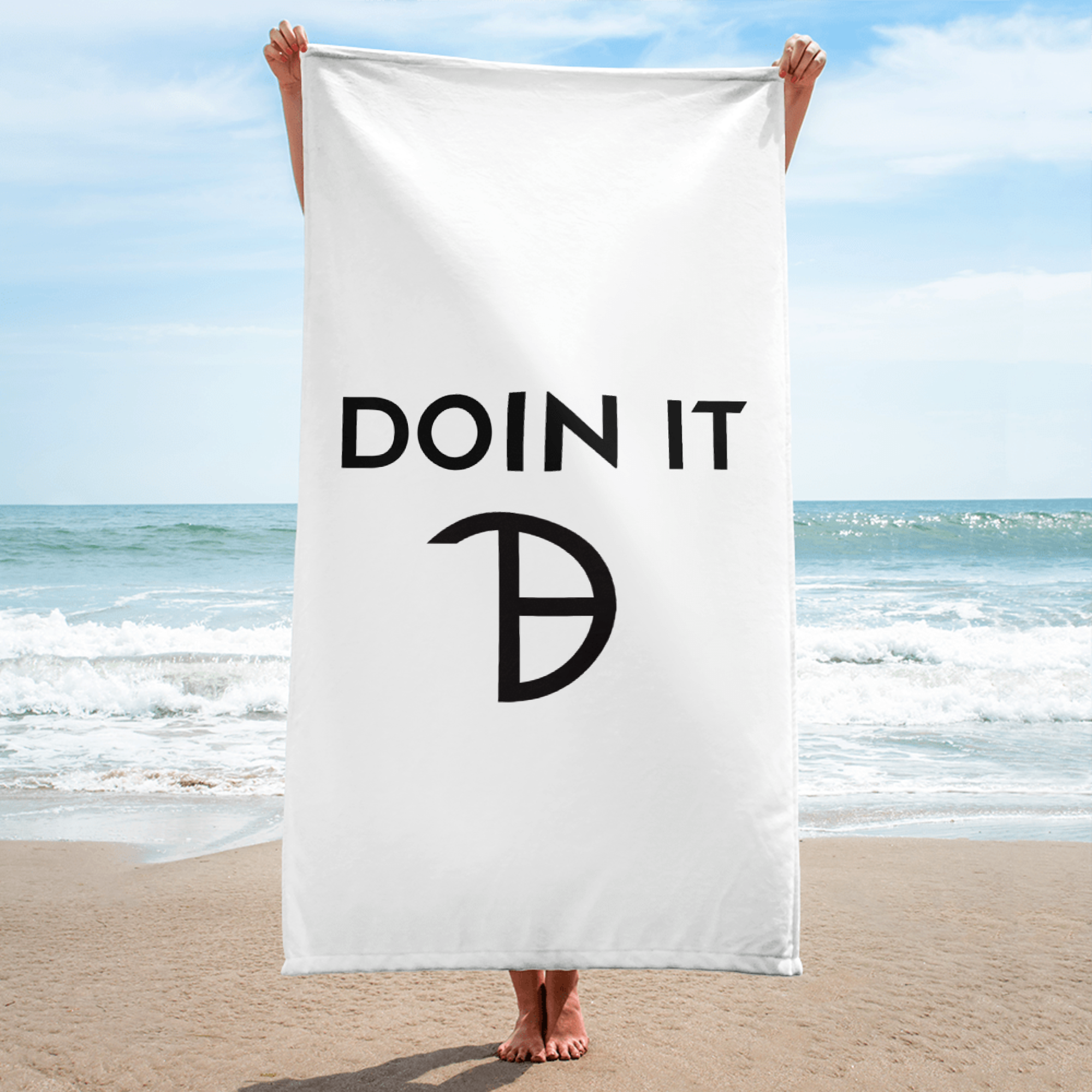 A girl standing on a beach holding a large white beach towel with the words 'DOIN IT' printed on it, obscuring their face and upper body.  bossswamee.com