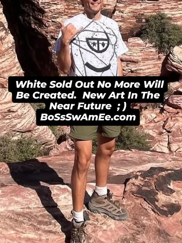 Man standing outdoors on rocky terrain wearing a white T-shirt, olive shorts, and hiking shoes, with a note about new art projects at BoSSwAmEe.com.
